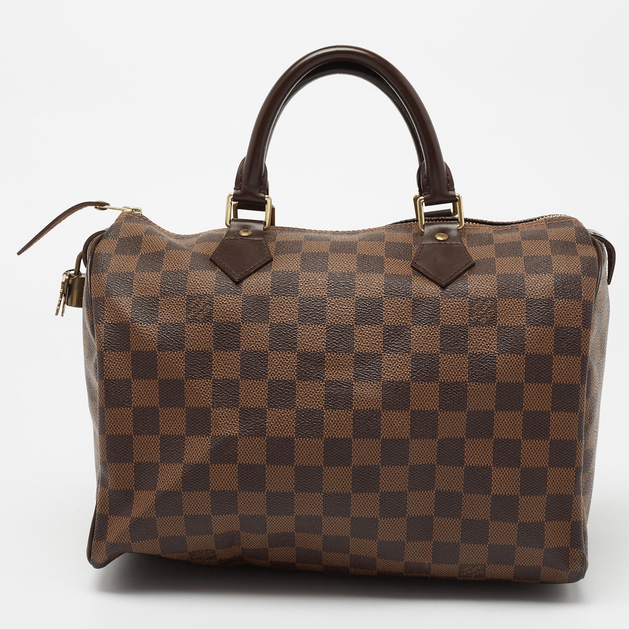 Created to provide you with everyday ease, this Louis Vuitton Speedy 30 bag features dual handles and a roomy fabric-lined interior. The usage of the signature Damier Ebene canvas in its construction offers instant brand identification. Gold-tone
