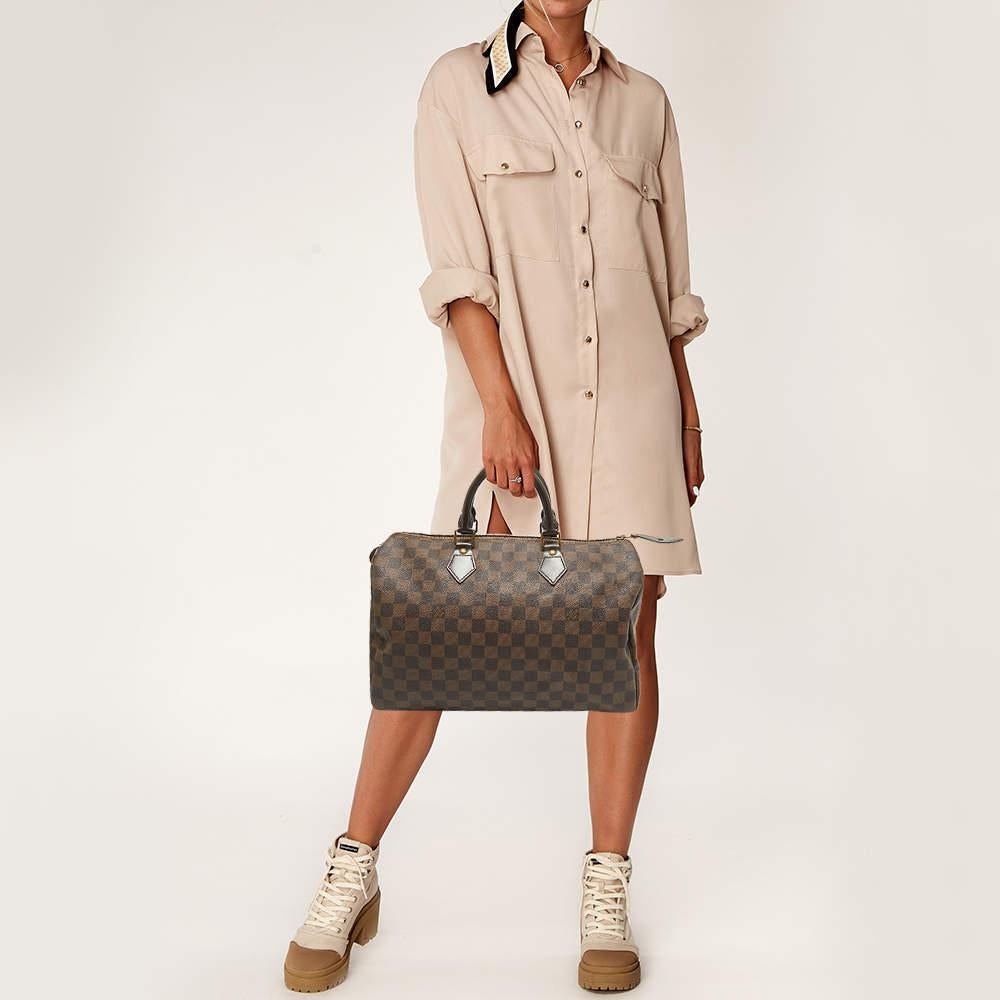 Titled as one of the greatest handbags in the history of luxury fashion the Speedy from Louis Vuitton was first created for everyday use as a smaller version of their famous Keepall bag. This Speedy comes crafted from Damier Ebene coated canvas with