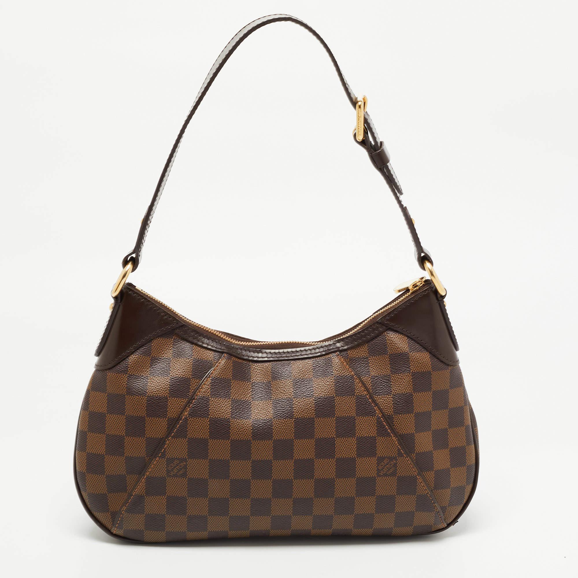 Louis Vuitton's handbags are popular owing to their high style and functionality. This Thames PM bag is crafted from signature Damier Ebene canvas and comes with a shoulder strap. The zip top closure opens to a canvas-lined interior that will house
