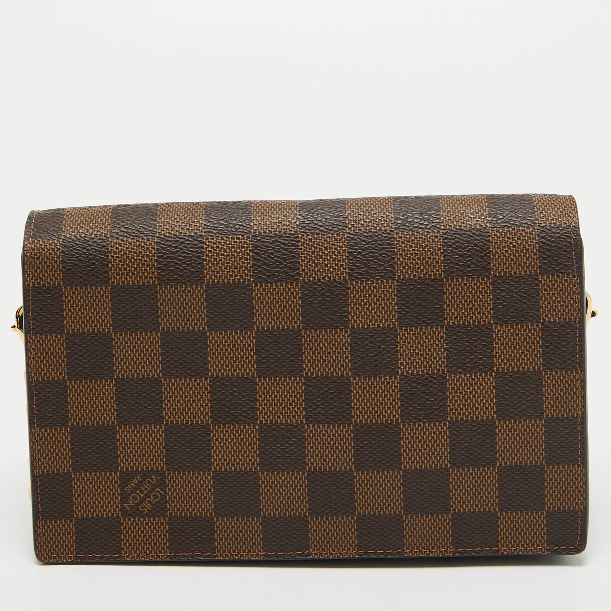 The Louis Vuitton Vavin Chain Wallet exudes sophistication with its signature brown checkered Damier Ebene pattern on coated canvas. The compact design features a gold-tone chain strap, multiple card slots, and a zippered pocket, seamlessly blending