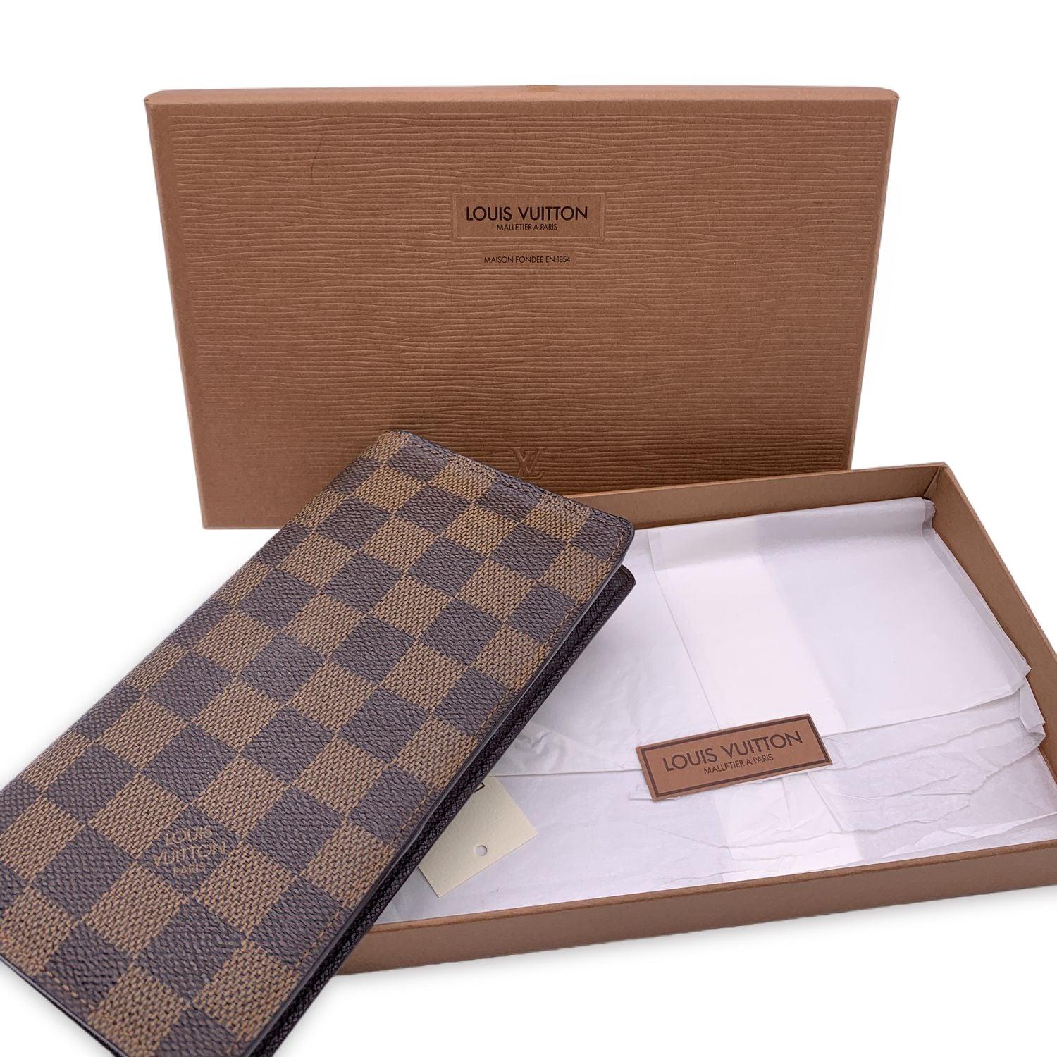 Louis Vuitton Damier Ebene canvas Vertical Wallet. Brown leather inside. 2 side pockets and 6 credit card slots inside. Authenticity Serial Number inside one of the pockets. 'LOUIS VUITTON Paris - made in France' embossed inside. Condition B - VERY