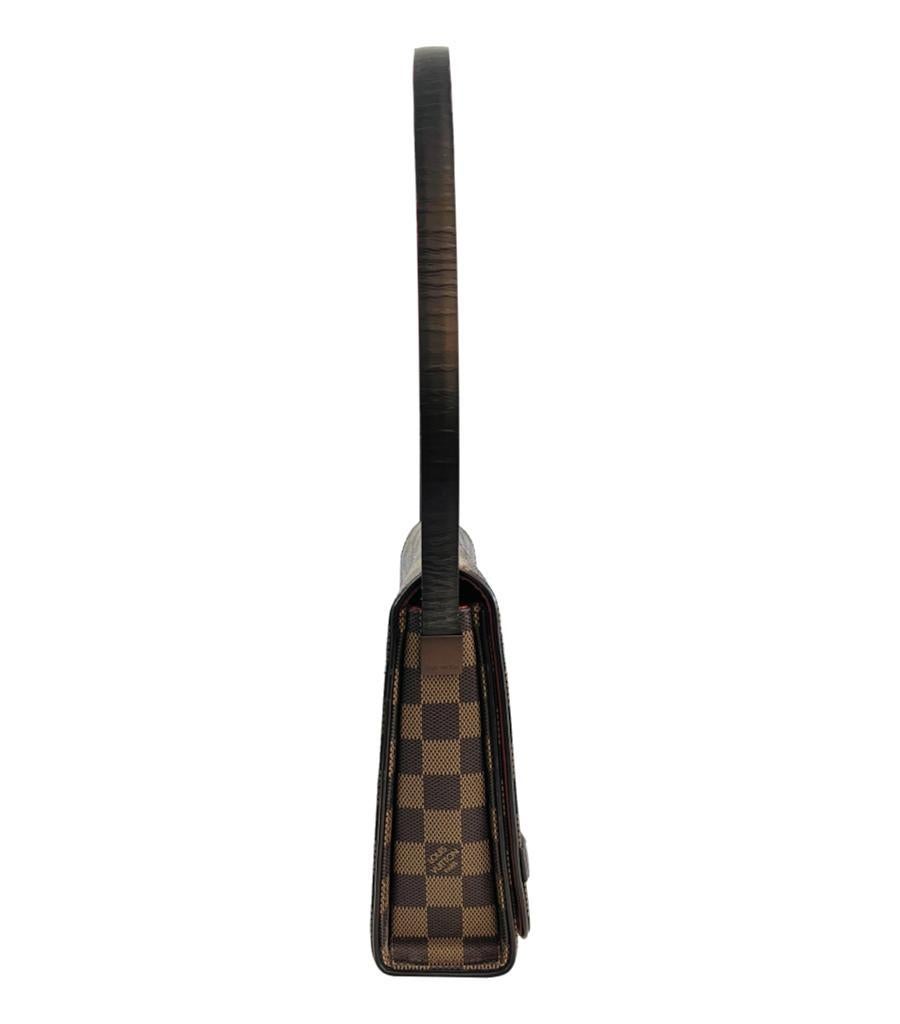 Louis Vuitton Damier Ebene Tribeca Tasche aus beschichtetem Segeltuch
Braune Tasche aus dem charakteristischen Damier Ebene Canvas.
Mit Schulterriemen aus Leder und vertikalem Detail auf der Vorderseite mit eingravierter silberner 