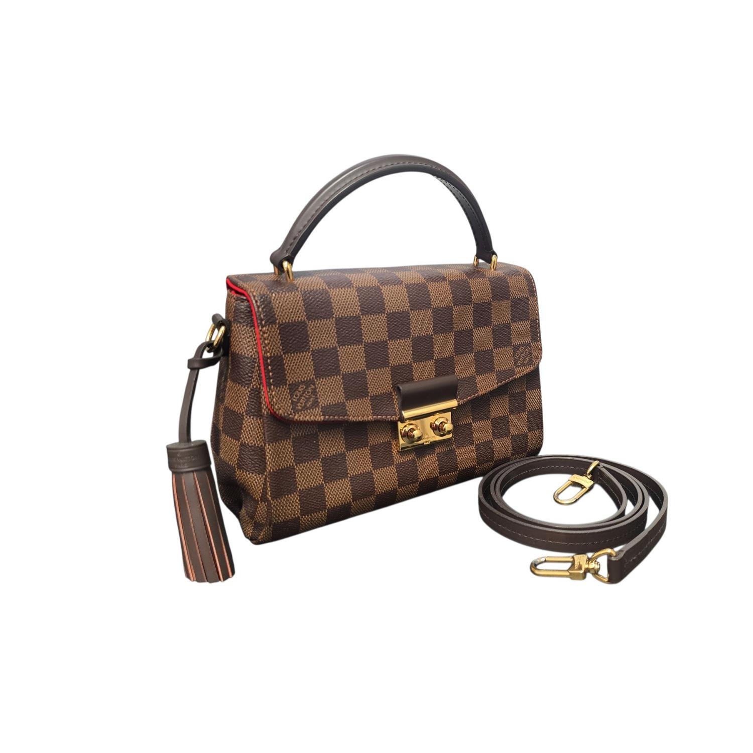 La borsa a tracolla Louis Vuitton Damier Ebene Croisette è un accessorio compatto ed elegante realizzato in resistente tela Coates con finiture in pelle. Presenta una chiusura sicura a S, una nappina rimovibile e un versatile cinturino da 22 pollici