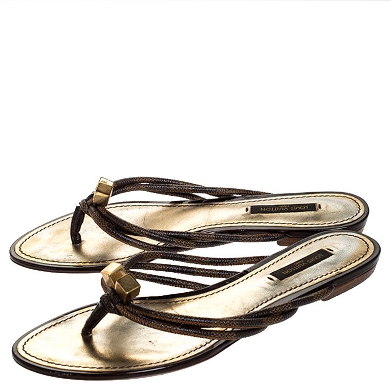 Estas impresionantes chanclas de Louis Vuitton han sido diseñadas para ofrecer estilo y comodidad. Tienen estilo de cosa y están confeccionados con la lona Damier Ebene característica de la marca. Presentan adornos de cubos dorados y un acabado