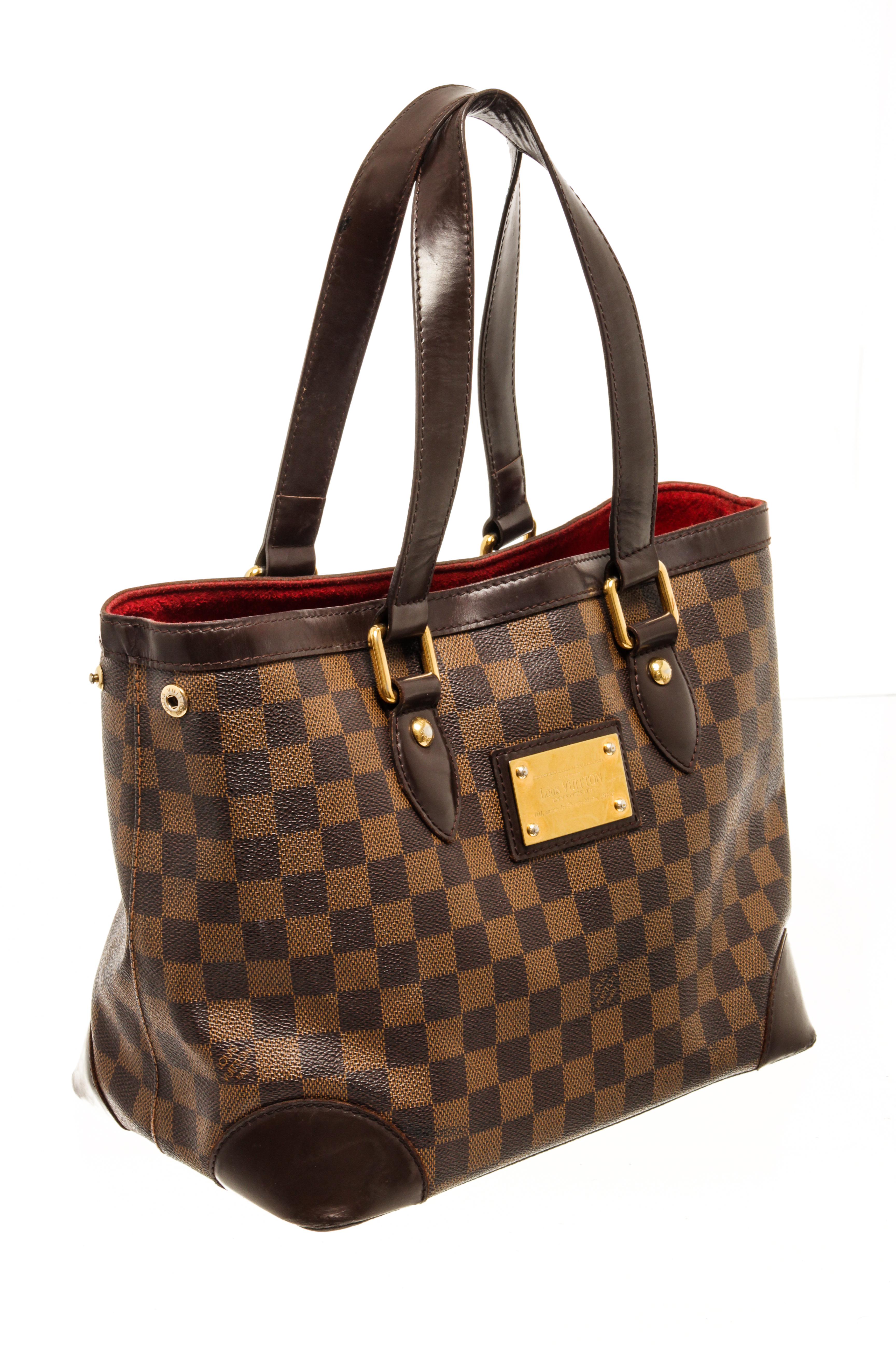 Louis Vuitton Damier Ebene Hampstead PM with clasp closure, one zip interior pocket, gold hardware, red fabric lining.

80020MSC
