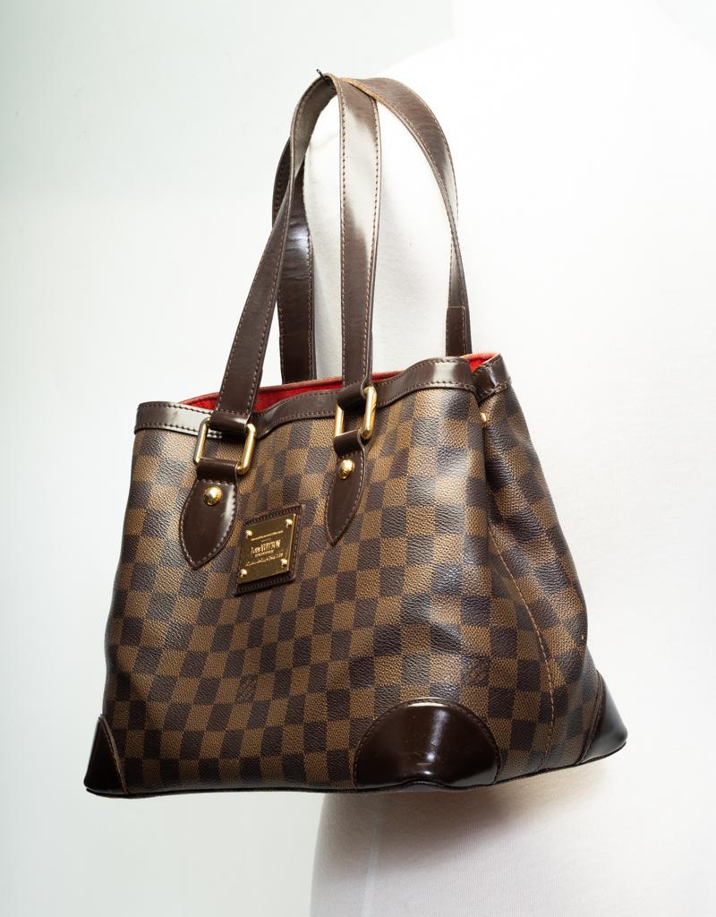This bag is made of brown coated canvas with Damier Ebene pattern and features chocolate brown leather finishes, gold tone hardware, dual shoulder straps and red alcantara interior lining. (Damier is French for checkerboard)

COLOR: Brown/Damier