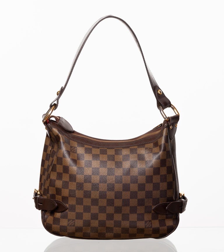 This bag is made from Damier Ebene coated canvas and features brass hardware, flat leather shoulder strap, chocolate leather trim, single pocket at front flap with buckle-closure and red alcantara lining. (Damier is French for checkerboard)

COLOR: