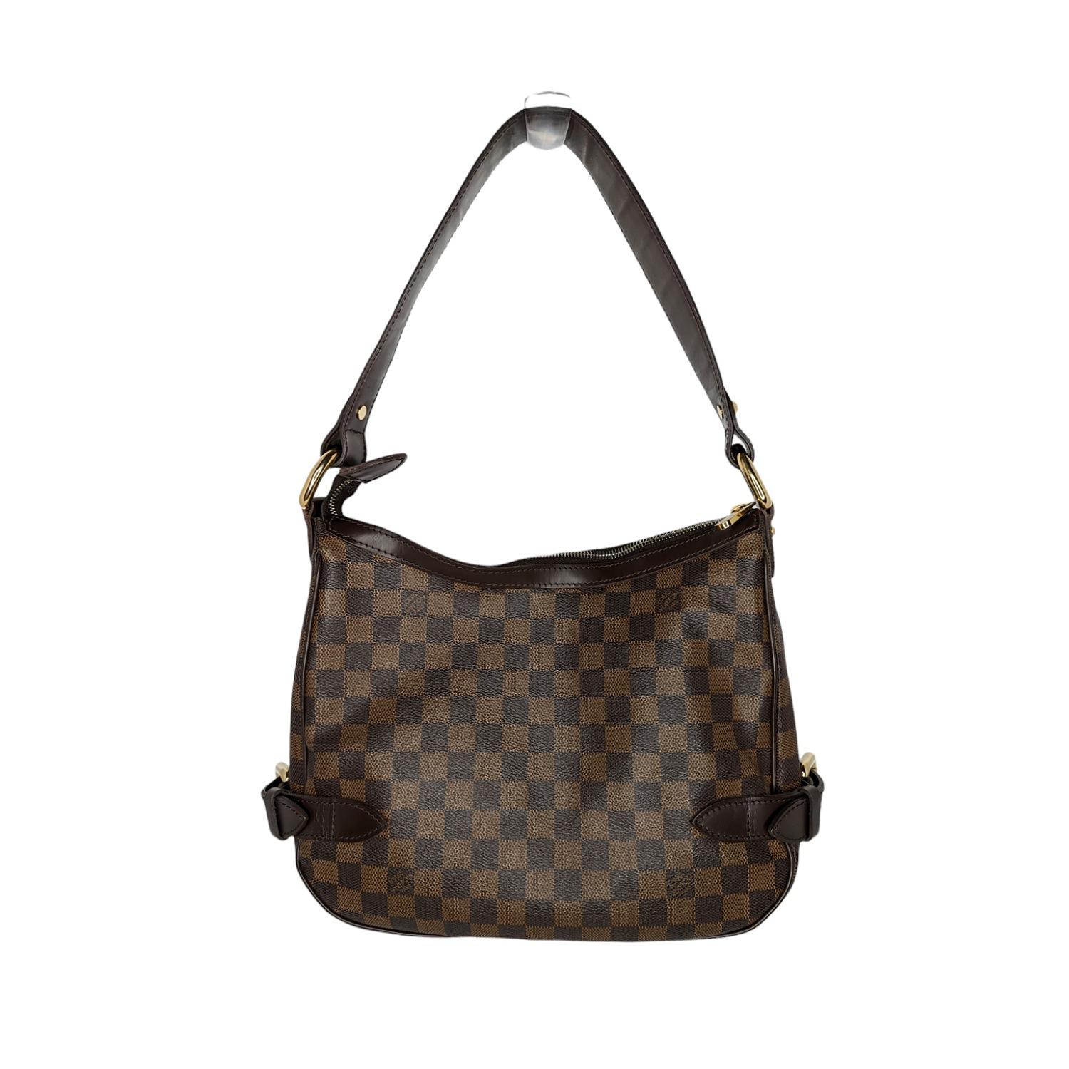This stylish Louis Vuitton Highbury Handbag is crafted of Damier Ebene coated canvas with leather trims and golden brass hardware pieces. It has a top zipper closure. The inside has two large separate compartments, an inside patch pocket and a cell