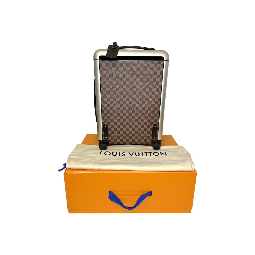 This stylish hard suitcase is crafted of Louis Vuitton Damier Ebene canvas with leather trimmings, a top handle, and state of the art pull and roller mechanisms with aluminum hardware. It has a wraparound zipper closure that opens to nylon