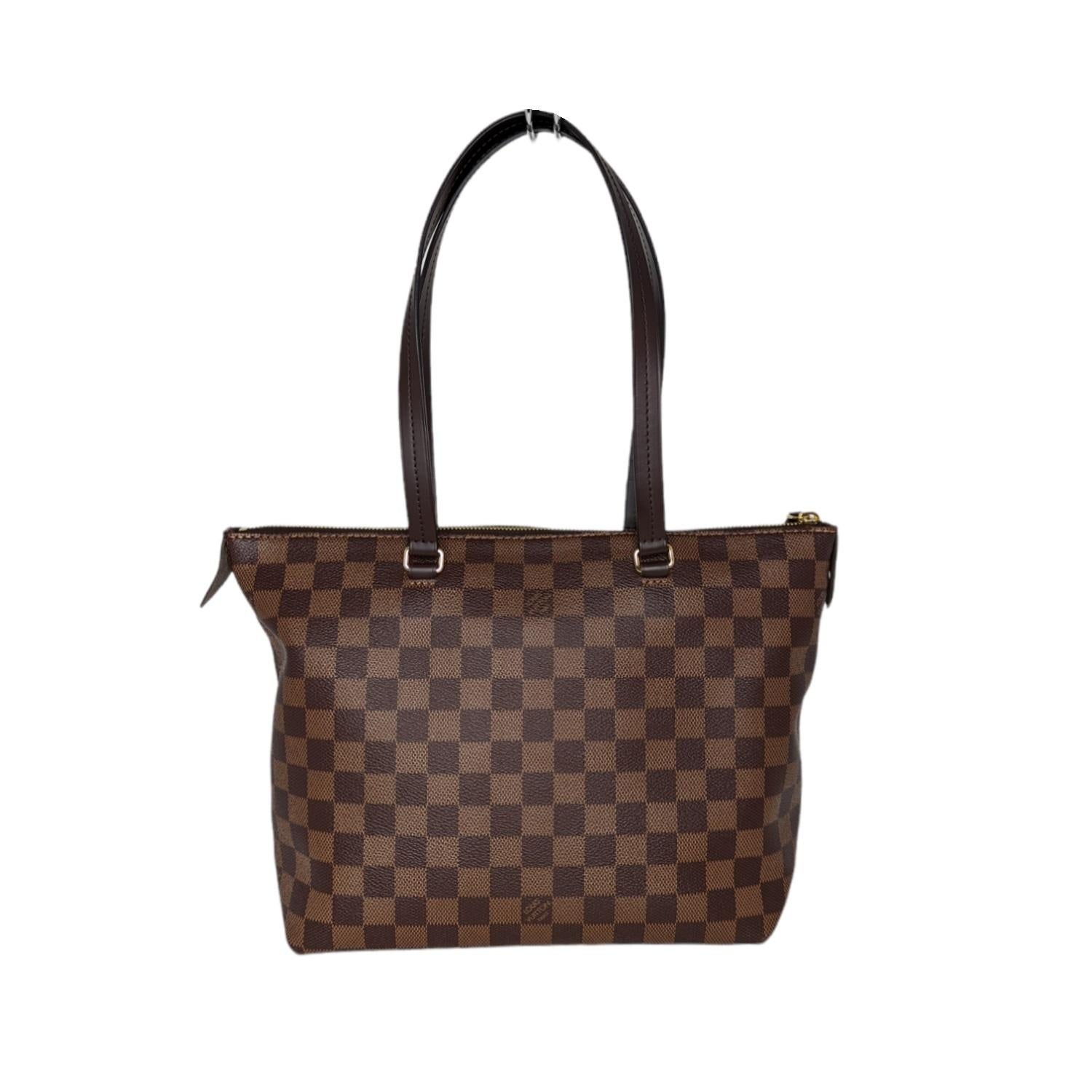 This stylish tote is crafted of Louis Vuitton Damier coated canvas in brown. The bag features a front zipper pocket, and chocolate brown leather trim and strap handles, with polished brass hardware. The top zipper opens the bag to a plum fabric