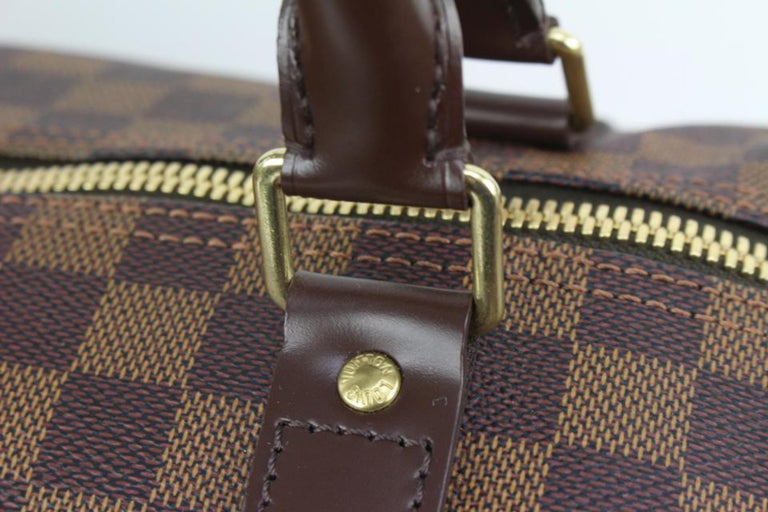 Louis Vuitton  A Louis Vuitton Damier Ebene Keepall Bandouliere 45 bag.  The duffel bag is crafted of damier checkered coated canvas with dark brown  leather accents. It features rolled leather top