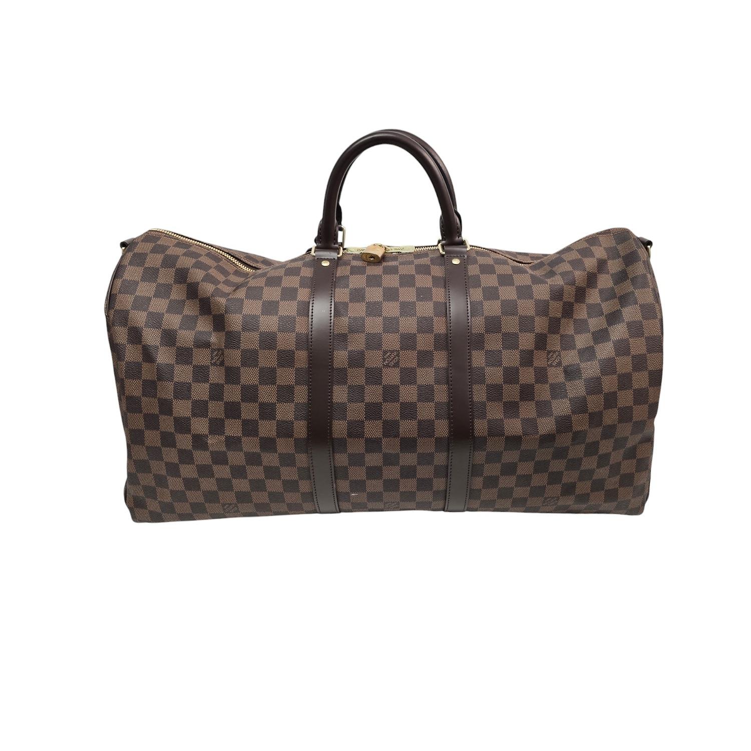 Enhance your travel style with the sophisticated Louis Vuitton Damier Ebene Keepall 55 Bandouliere. Crafted from luxurious Damier check canvas in brown, this travel bag features sturdy rolled leather handles and a removable shoulder strap for