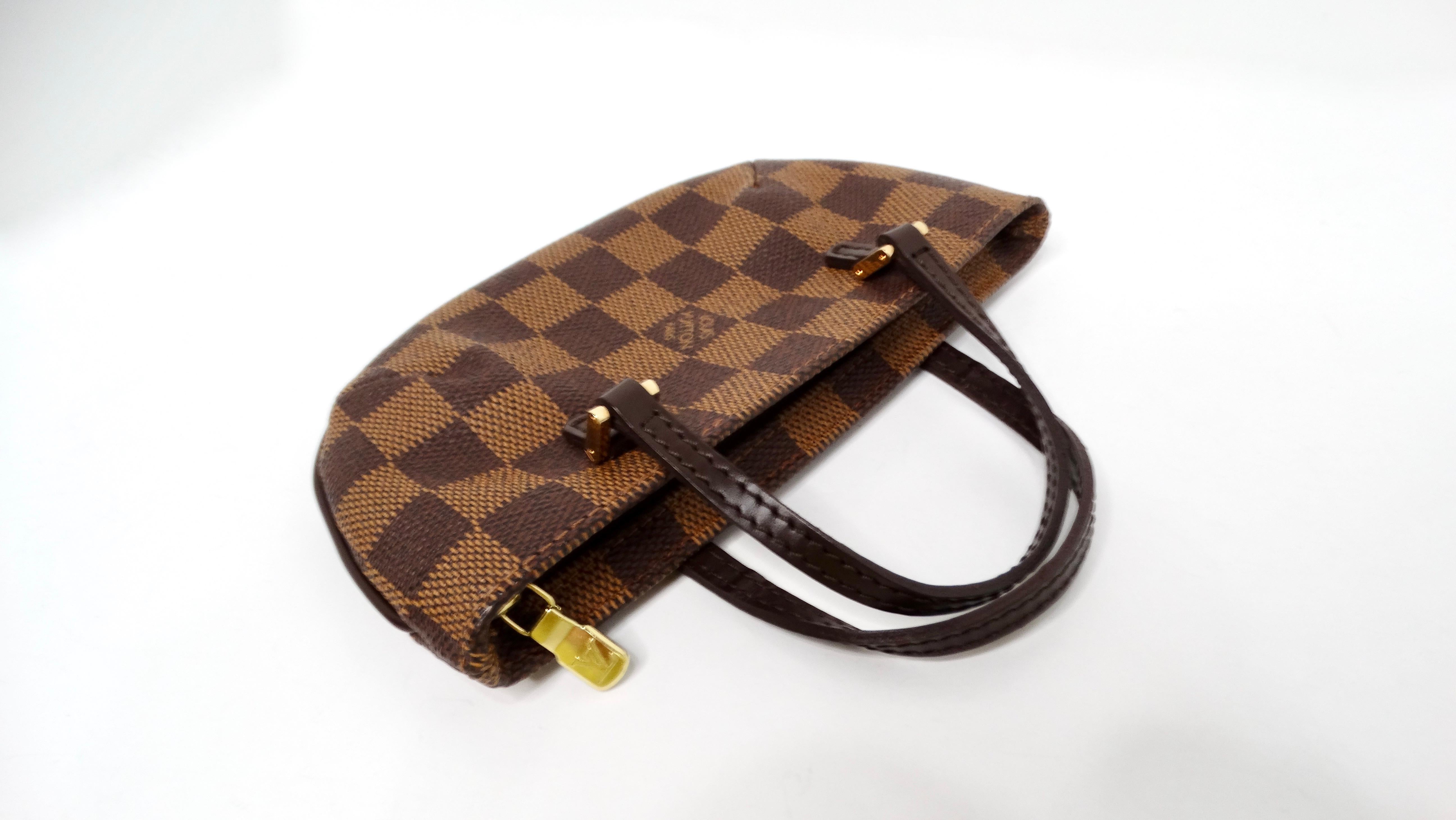 The Louis Vuitton Damier Ebene Manosque GM Pochette is an exquisite embodiment of luxury and functionality. Crafted from the iconic Damier Ebene coated canvas, this pochette features a rich brown checkerboard pattern that is both timeless and