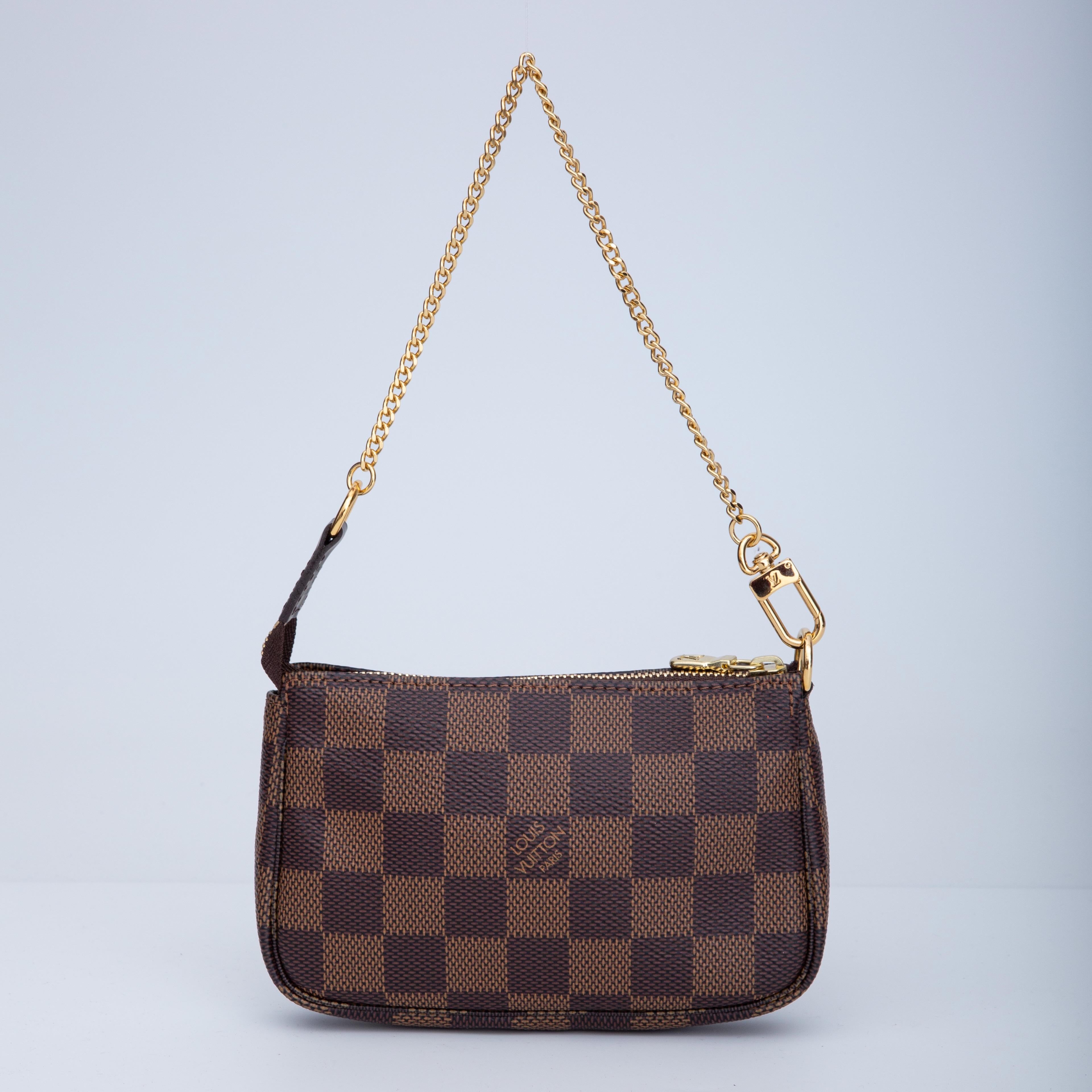 This pochette is made of damier eben coated canvas with dark lather finishes. The pochette has a thin polished gold chain strap that can attach to larger handbags. The top zipper opens to a red fabric interior.

COLOR: Brown/Damier ebene
MATERIAL: