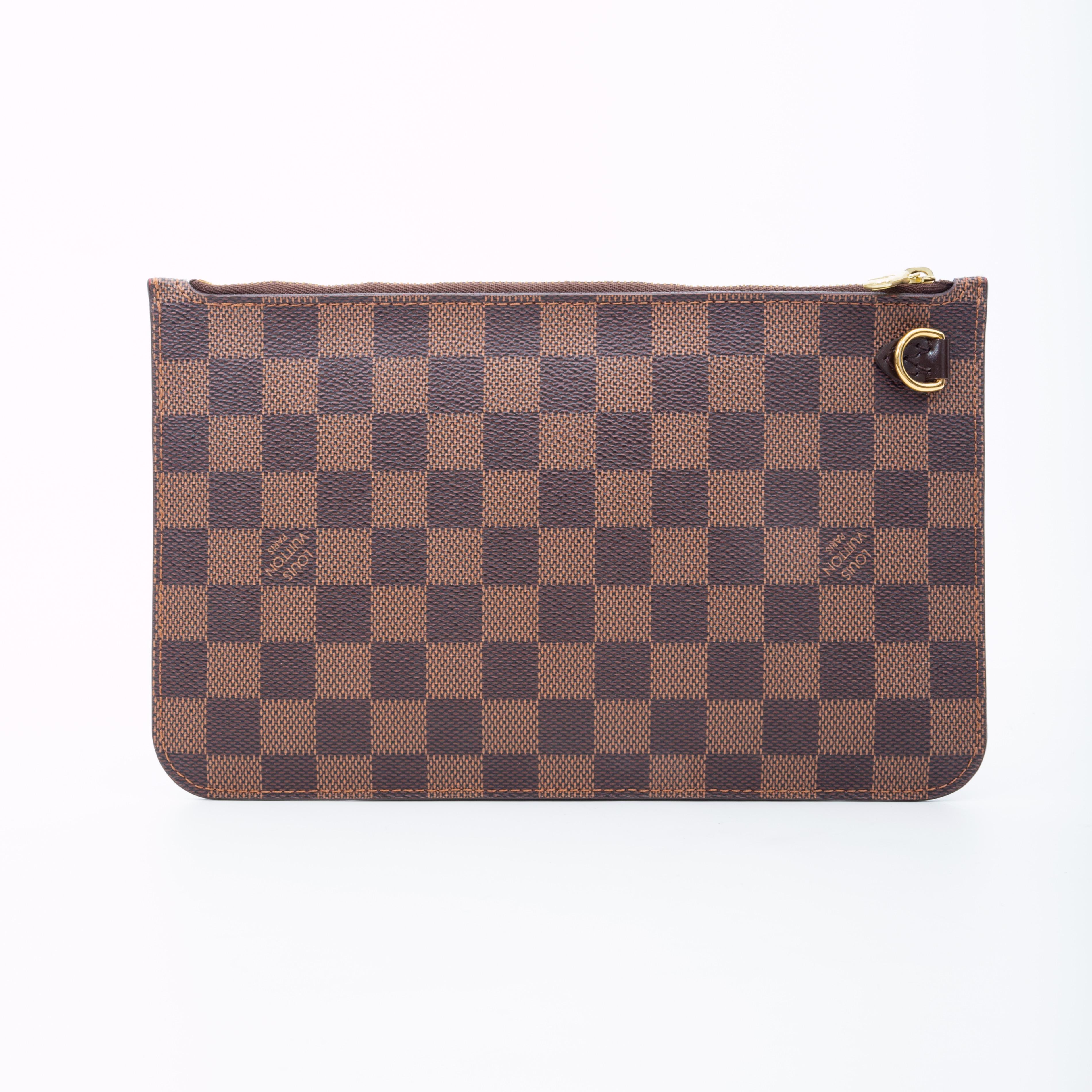 This clutch is made with brown Damier Ebene coated canvas and features leather details, gold tone hardware, top zip closure and red woven fabric lining with an interior slip pocket.

COLOR: Brown Damier Ebene
MATERIAL: Coated canvas
DATE CODE: