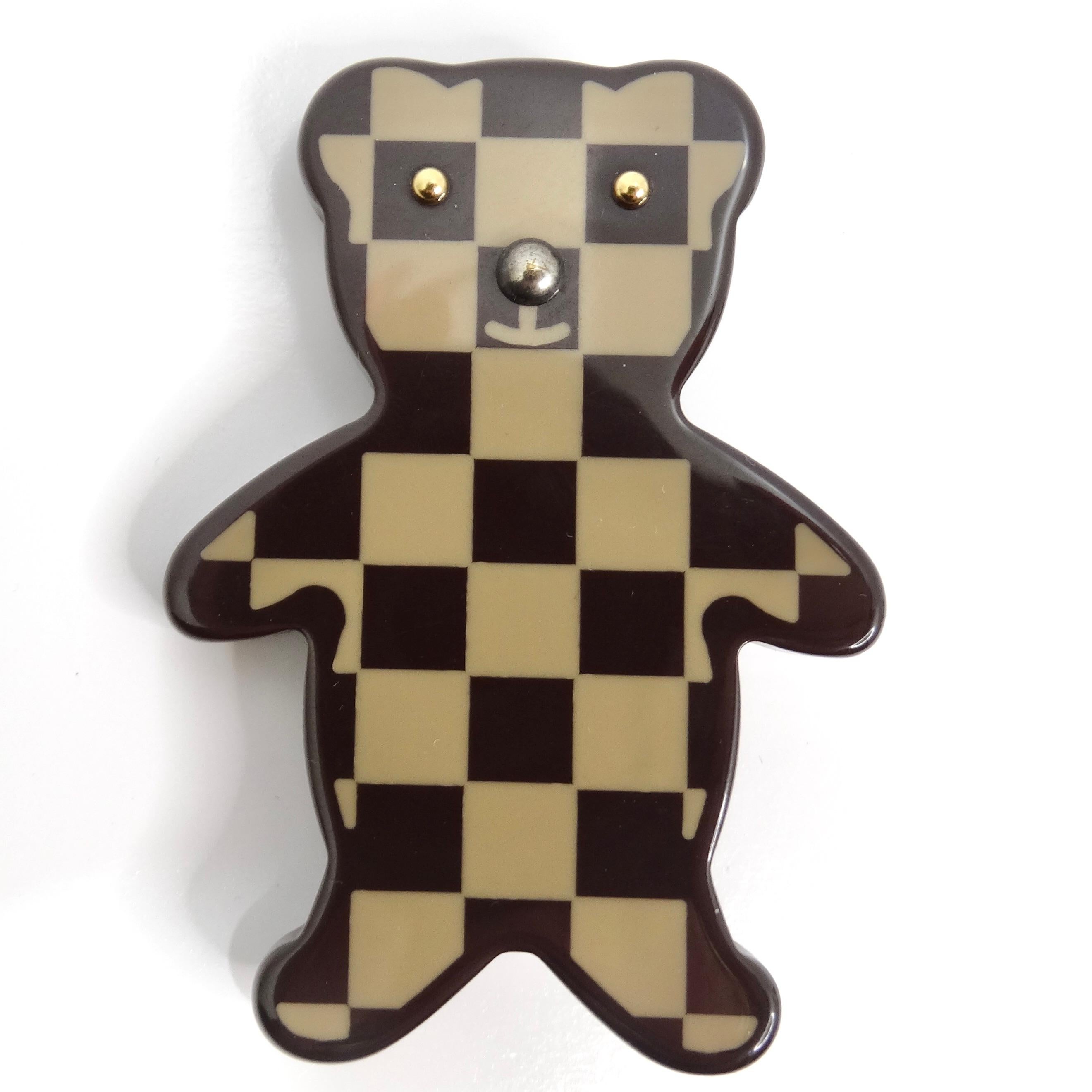 Introducing the exquisite Louis Vuitton Damier Ebene Resin Teddy Bear Brooch, a playful and luxurious accessory that adds a touch of sophistication to any ensemble. Crafted from high-quality resin, this adorable brooch is designed in the shape of a