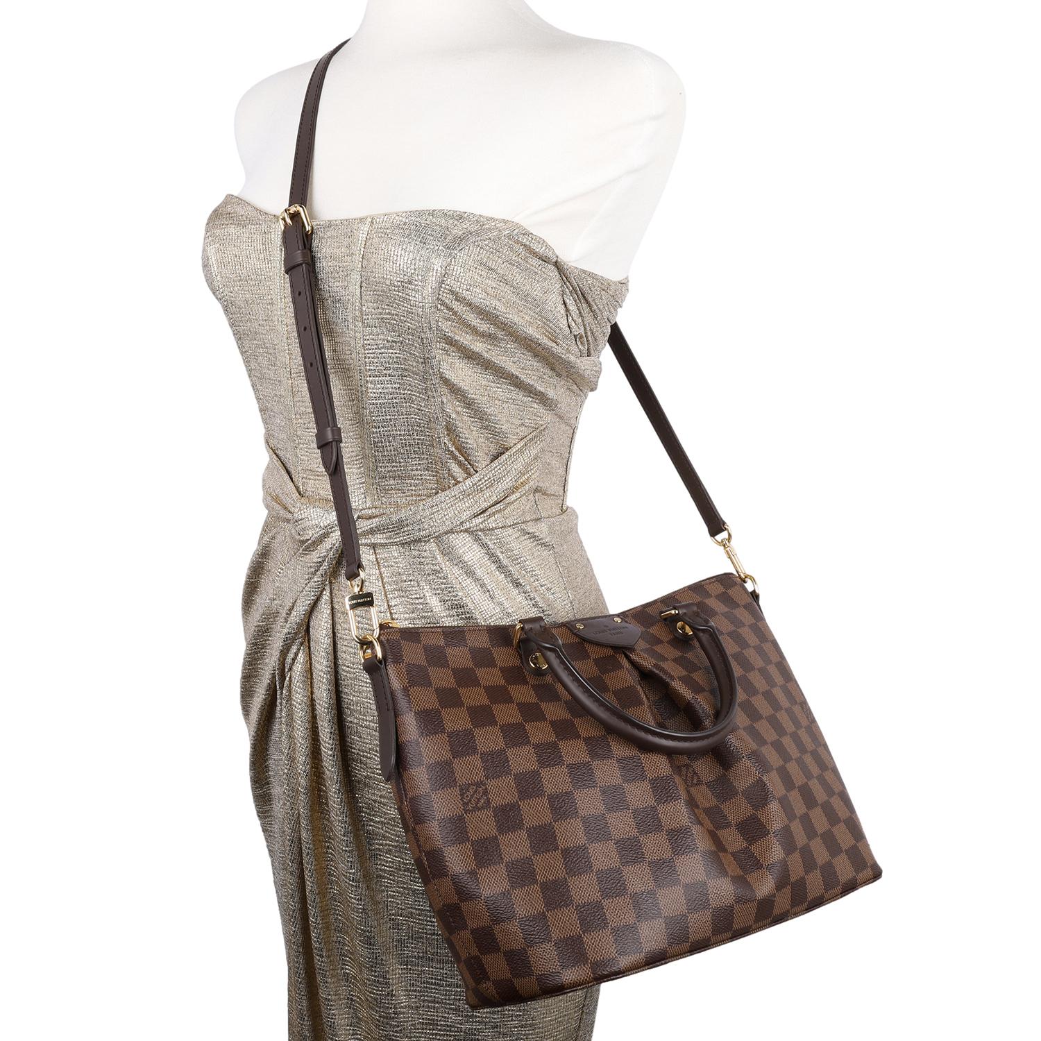 Authentic Louis Vuitton Brown Damier Ebene Sienna crossbody bag. This chic bag features Louis Vuitton Damier Ebene coated canvas in brown, zipper top closure, an adjustable dark brown leather shoulder strap, dual rolled leather handles, brass