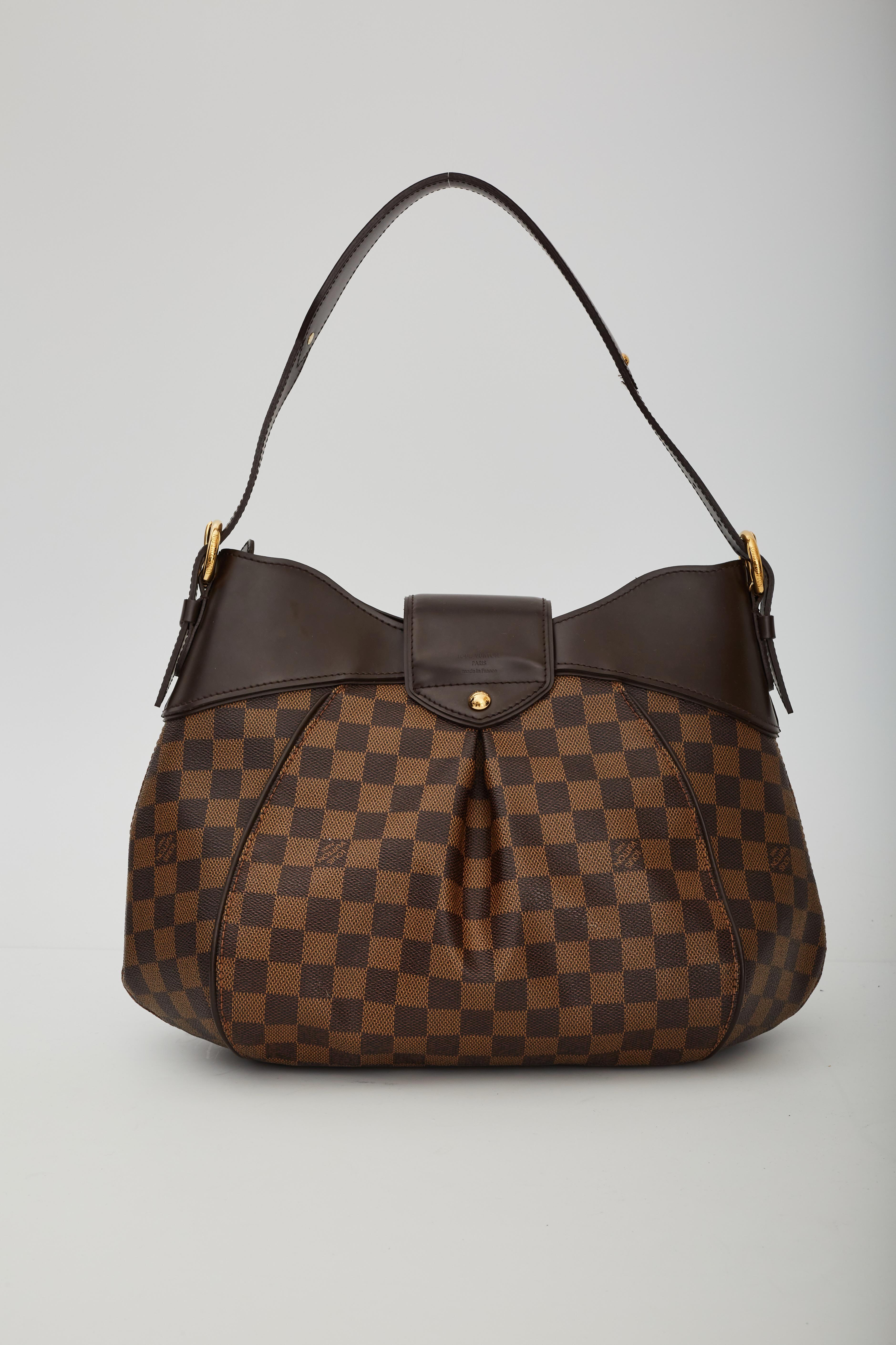 This shoulder bag is made of Louis Vuitton Damier check canvas. The bag features adjustable leather shoulder straps and trim. The bag opens with a gold press-lock and top zipper to a partitioned crimson red microfiber interior with pockets.

COLOR: