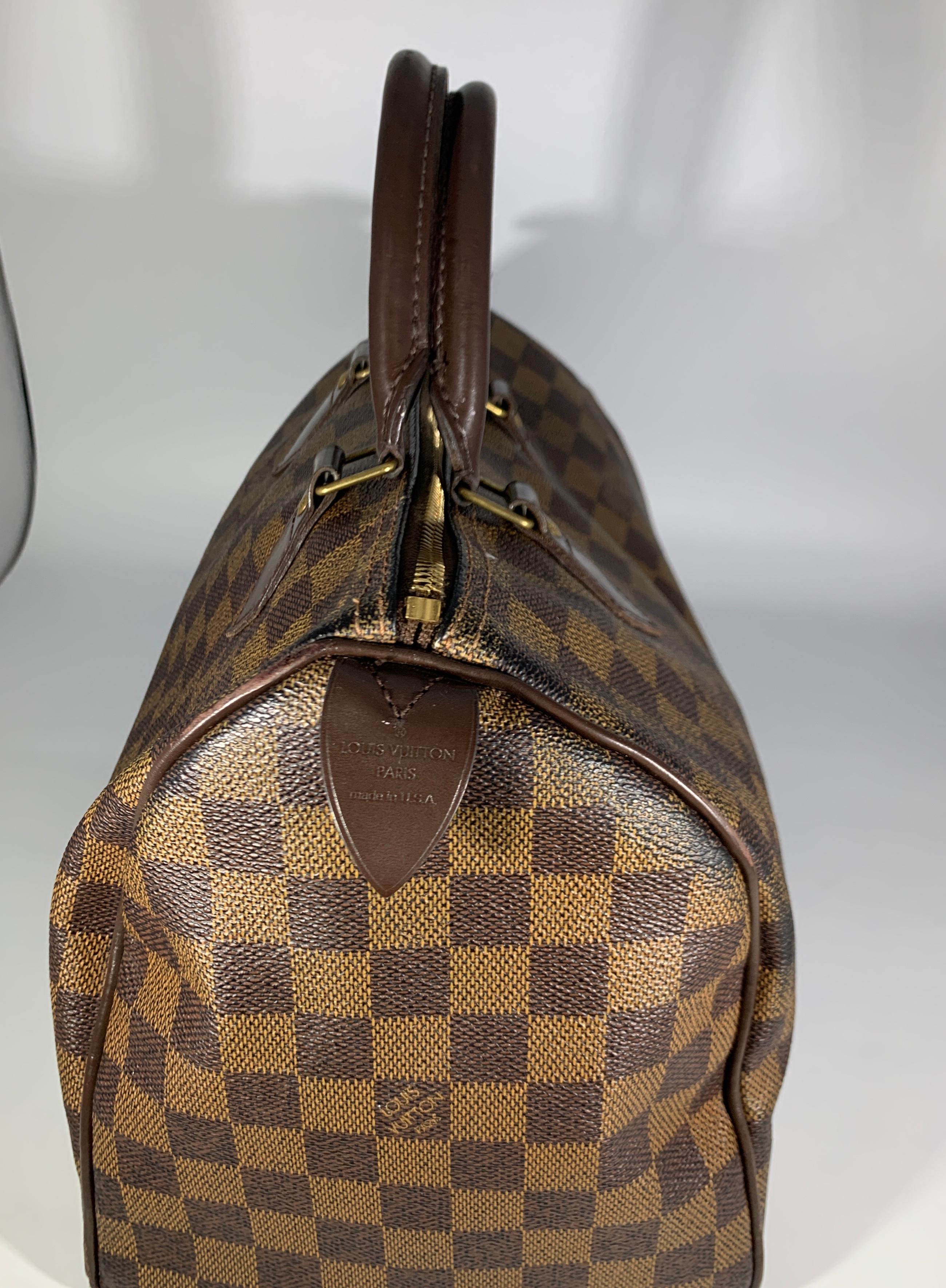 This is an authentic LOUIS VUITTON Damier Ebene Speedy 30 . This stylish doctor style tote is crafted in Louis Vuitton Damier checkered coated canvas in brown. It features brown leather rolled top handles detailed with polished brass hardware. The