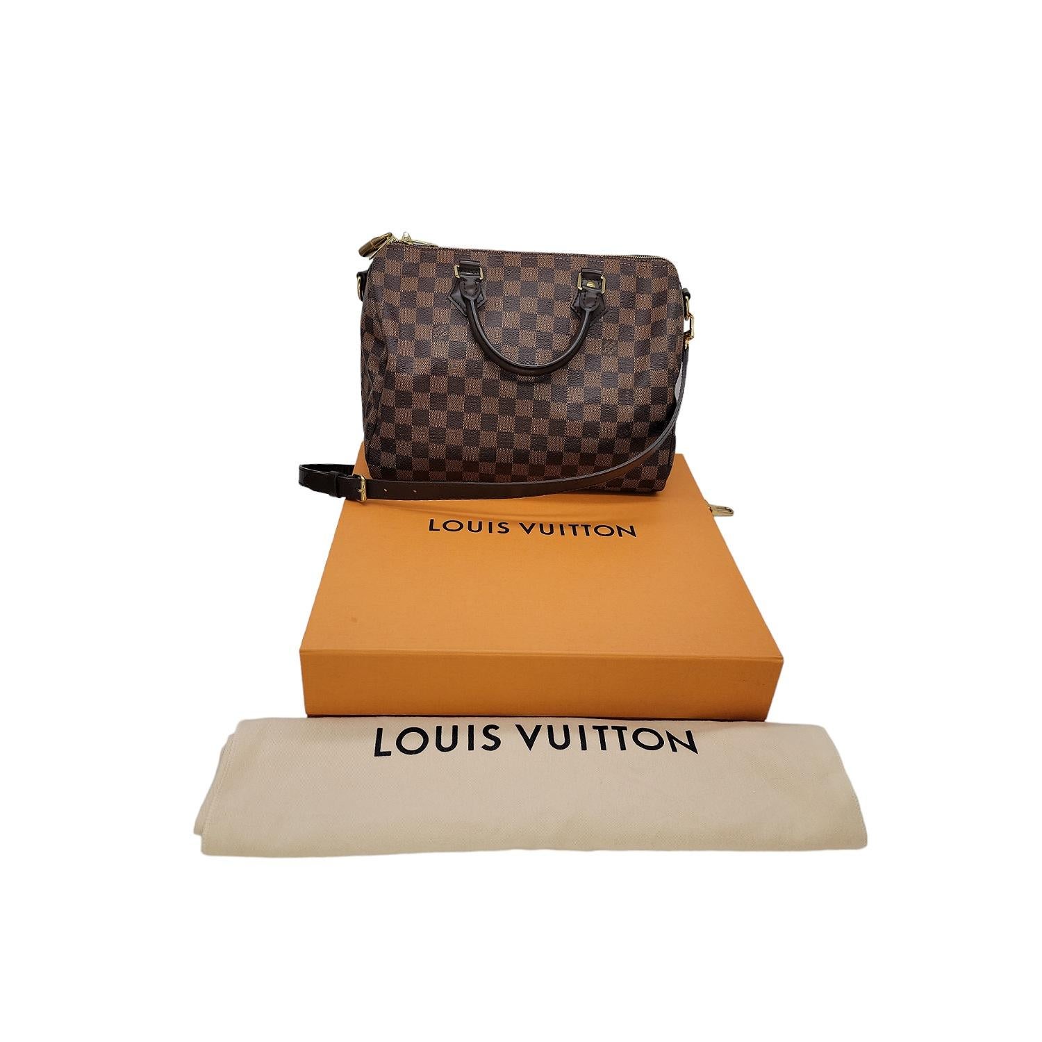 This Louis Vuitton Speedy Bandouliere 30 was made in the U.S.A. and it is finely crafted of the classic Louis Vuitton Damier Ebene coated canvas with leather trimming and gold-tone hardware features. It has dual rolled leather top handles a