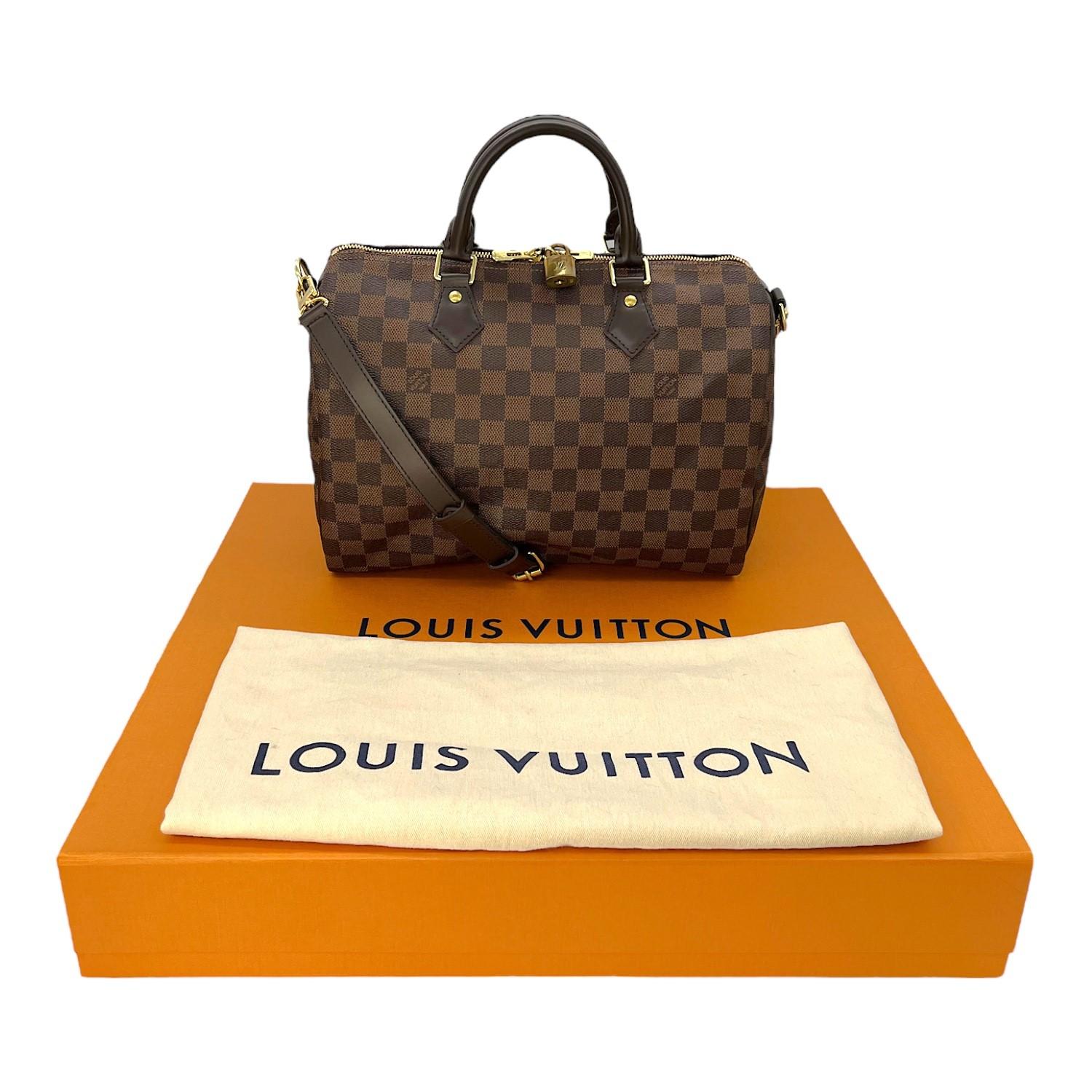 This Louis Vuitton Speedy Bandouliere 30 was made in the USA and it is finely crafted of the classic Louis Vuitton Damier Ebene coated canvas with leather trimming and gold-tone hardware features. It has dual rolled leather top handles and it has a