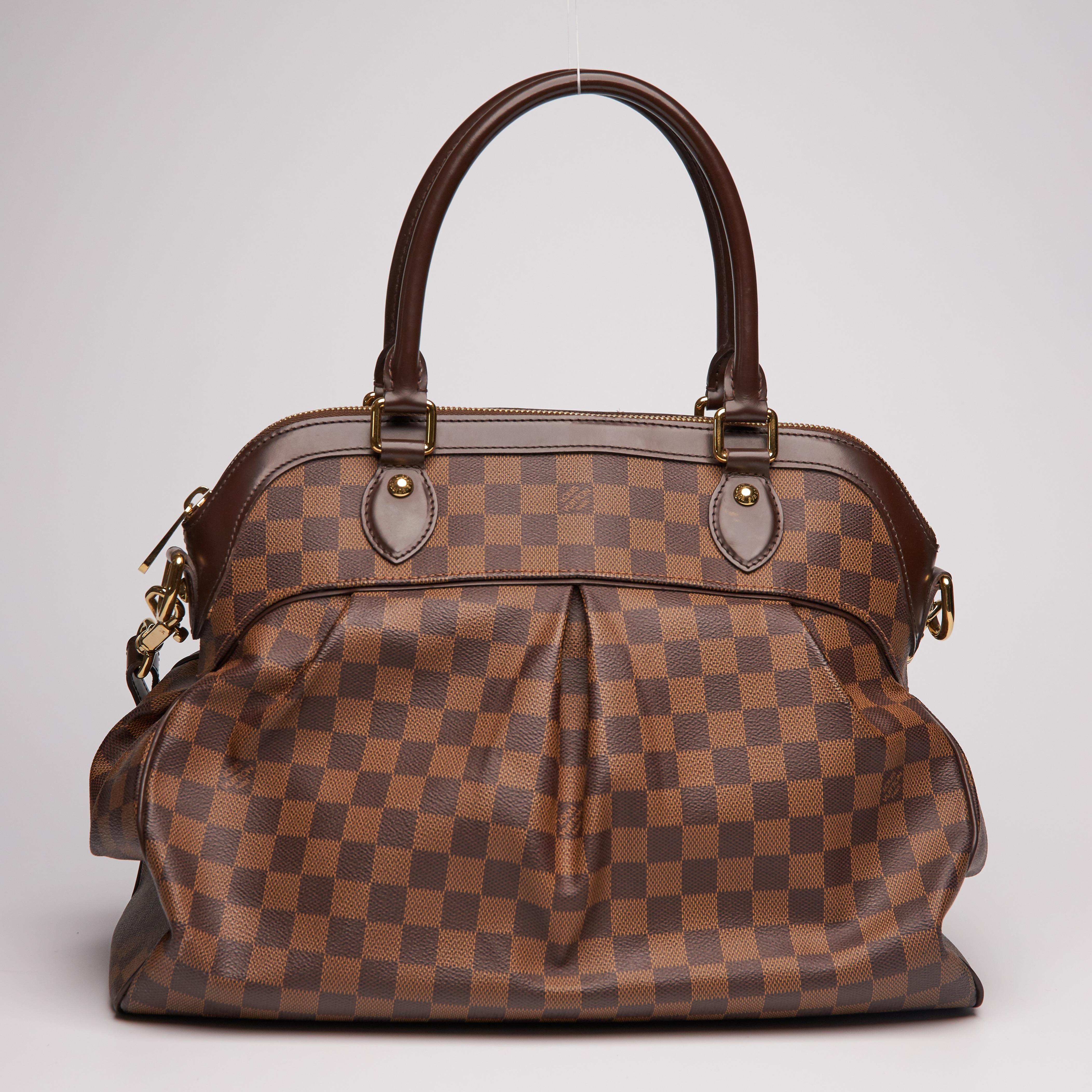 This bag is named after the glorious Trevi Fountain in Rome. The bag is made of signature Louis Vuitton damier ebene coated canvas. The bag features chocolate brown leather trim, dual rolled leather top handles, an optional adjustable shoulder