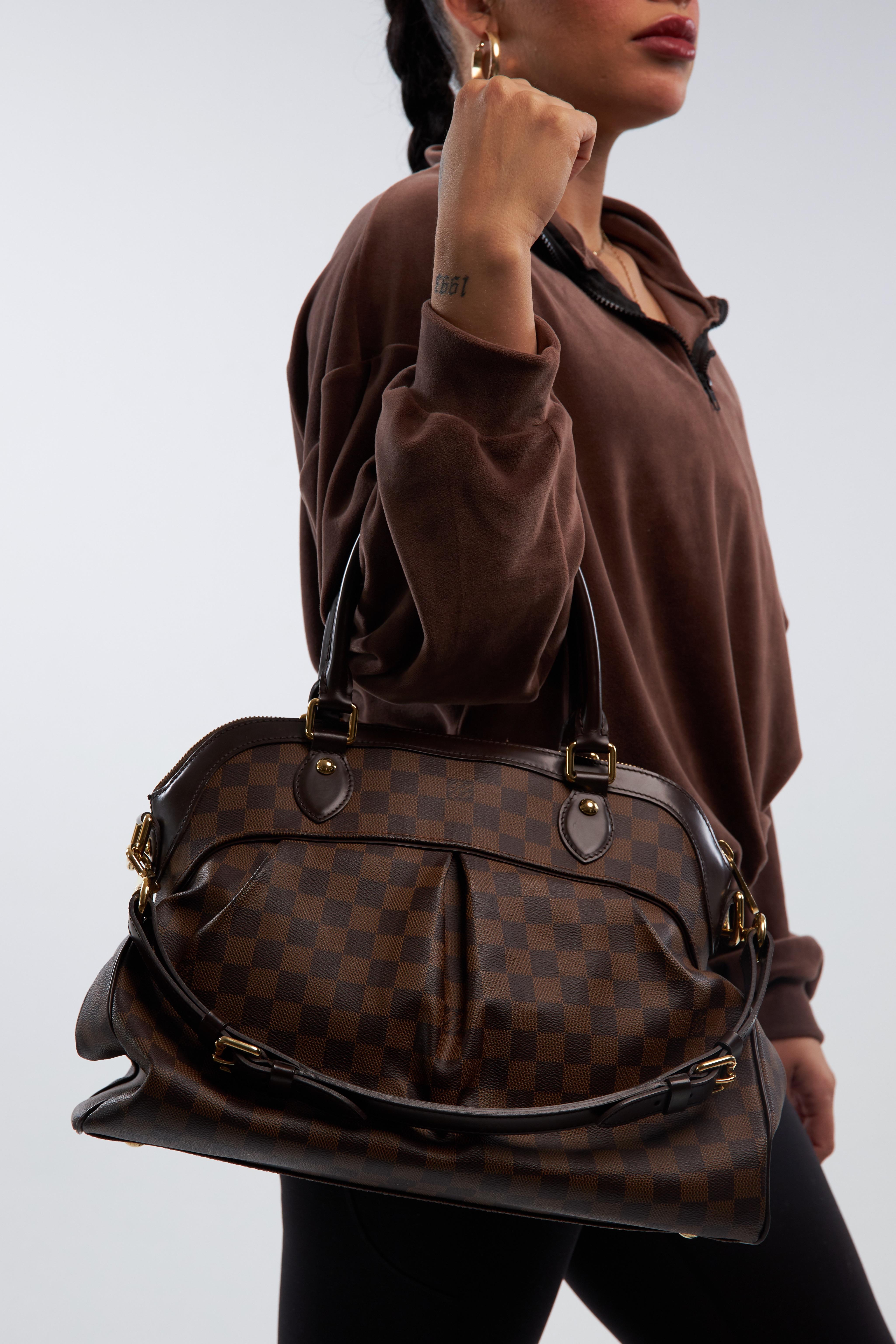 This bag is named after the glorious Trevi Fountain in Rome. The bag is made of signature Louis Vuitton damier ebene coated canvas. The bag features chocolate brown leather trim, dual rolled leather top handles, an optional adjustable shoulder