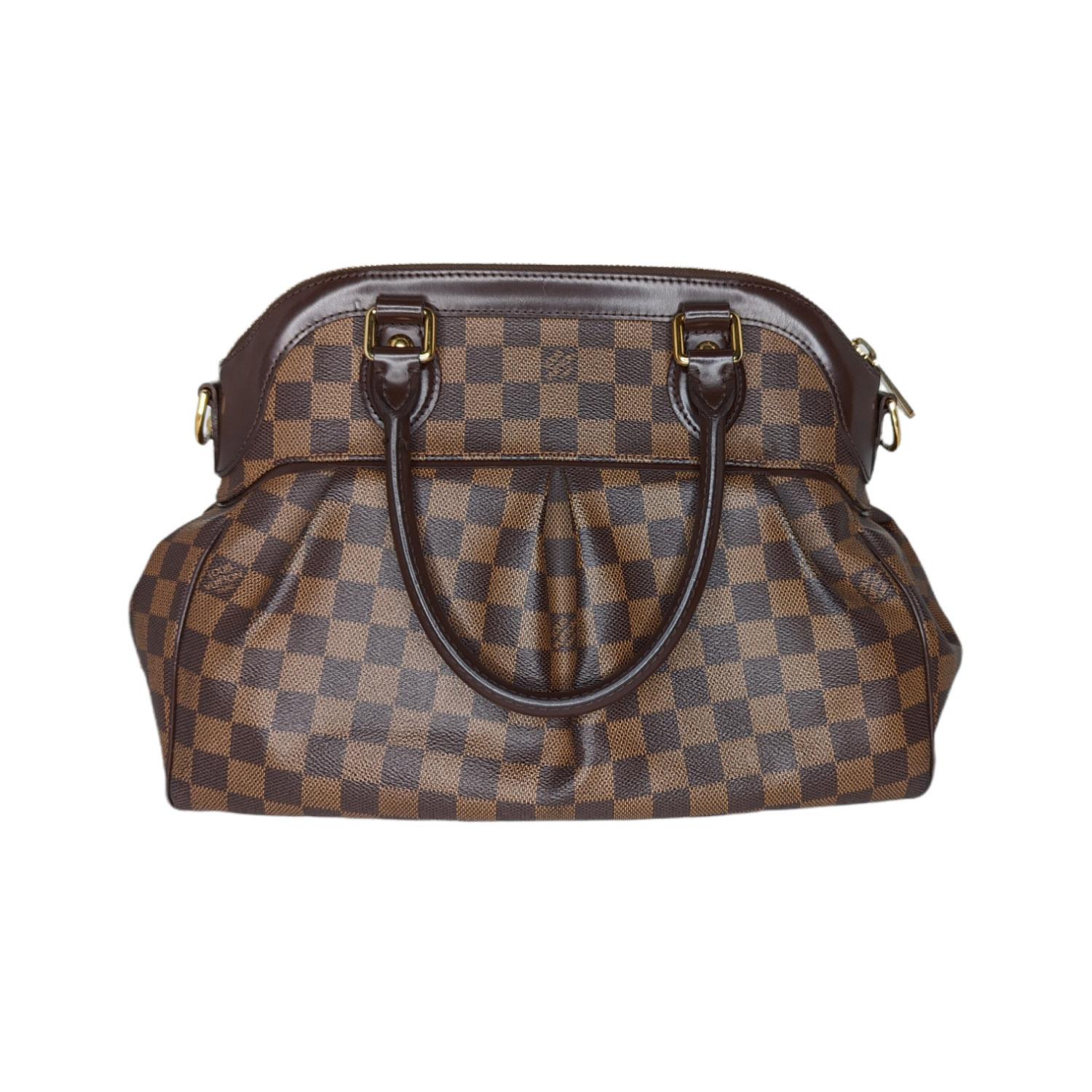 Damier Ebene coated canvas Louis Vuitton Trevi PM with brass hardware, dual rolled top handles, detachable shoulder strap, brown leather trim, crimson Alcantara lining, protective feet at base, dual interior slit pockets and zip closure at top.