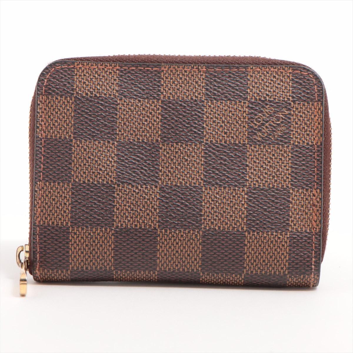 The Louis Vuitton Damier Ebene Zippy Coin Purse embodies the essence of sophistication and practicality. The Damier canvas exterior in shades of dark brown and light brown immediately catches the eye. The iconic checkered pattern, a hallmark of