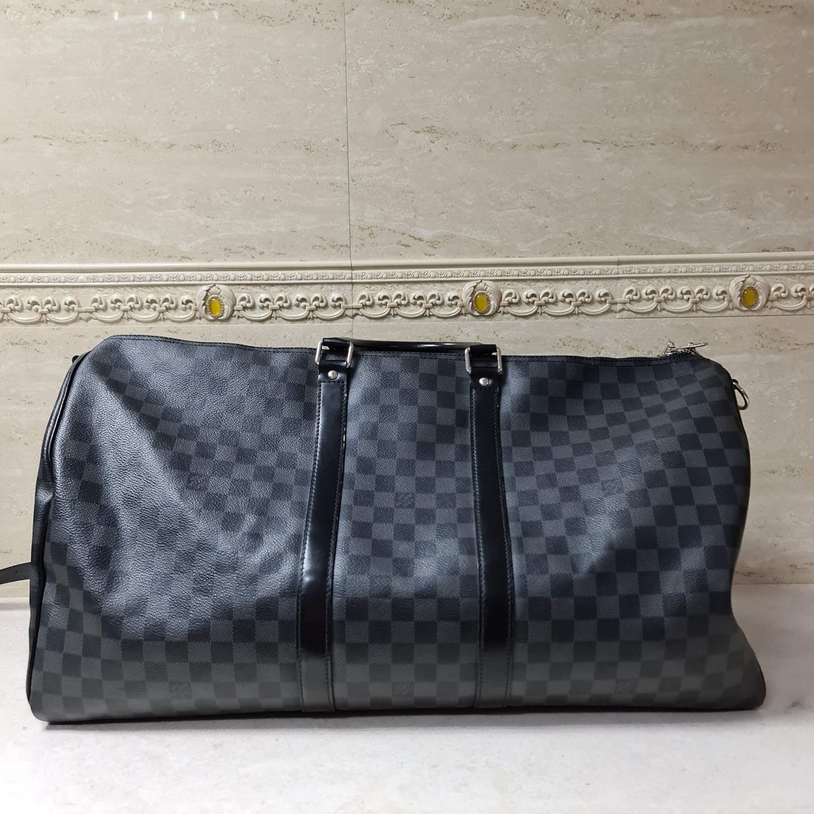 This Louis Vuitton Damier Graphite Canvas Keepall Bandouliere 55 Bag is perfect for travel or weekend getaway. With its ultra-spacious interior and the capability of folding flat, this bag is versatile as an additional travel piece. The Bandouliere