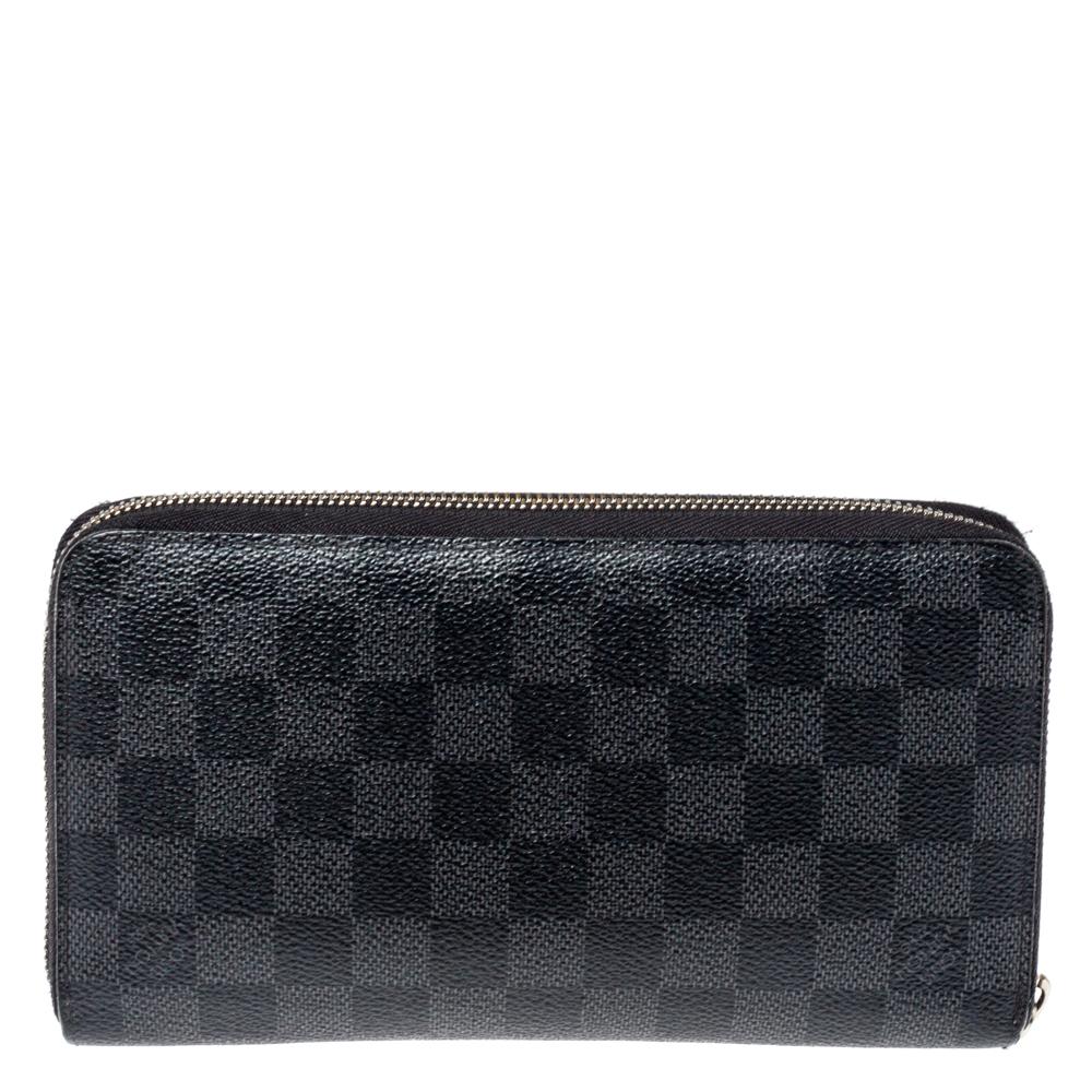 This Louis Vuitton Zippy wallet is conveniently designed for everyday use. Crafted from Damier Graphite canvas, the wallet features a 'Trunks & Locks' pattern and has a wide zip closure that opens to reveal multiple slots, leather-lined compartments