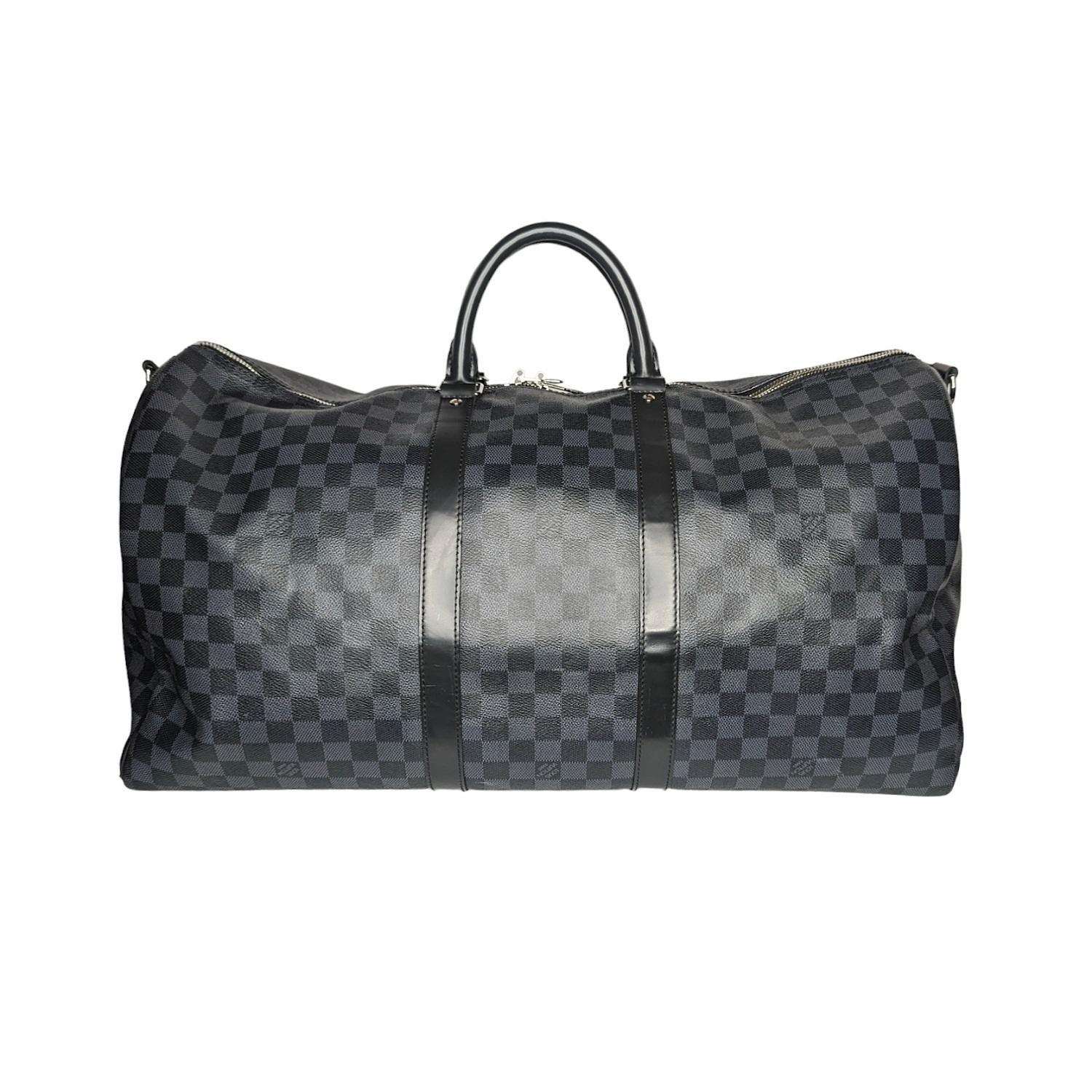 Louis Vuitton Damier Graphite Keepall Bandouliere 55. This travel bag is crafted of Louis Vuitton's signature Damier check canvas in black and gray. It features sturdy black rolled leather top handles, a removable shoulder strap, silver hardware,