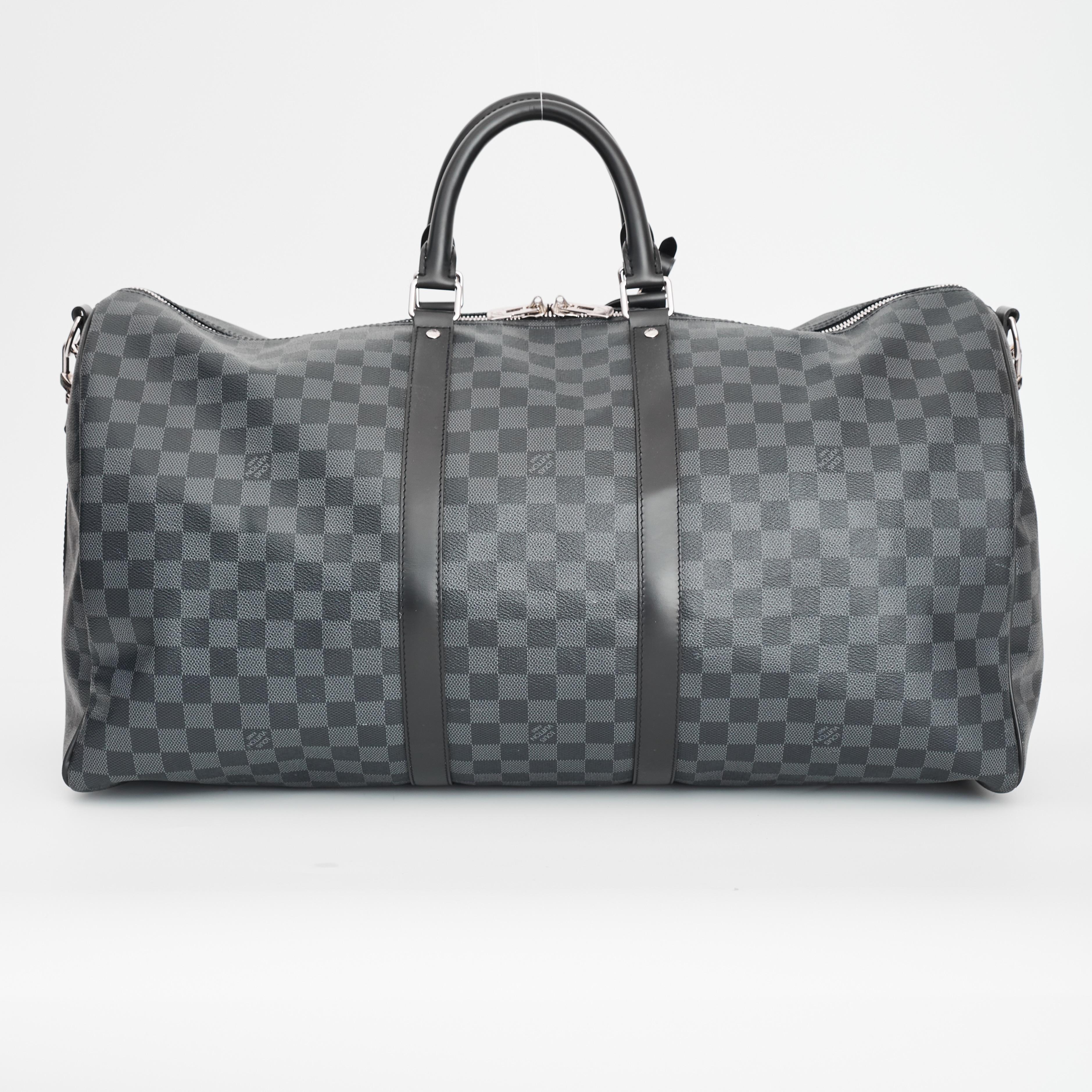 Louis Vuitton Weekender Bag. From the 2020 Collection. Made of black coated canvas and features damier graphite pattern, silver-tone hardware, leather details, rolled leather top handles, an adjustable shoulder strap, top zip closure, canvas lining