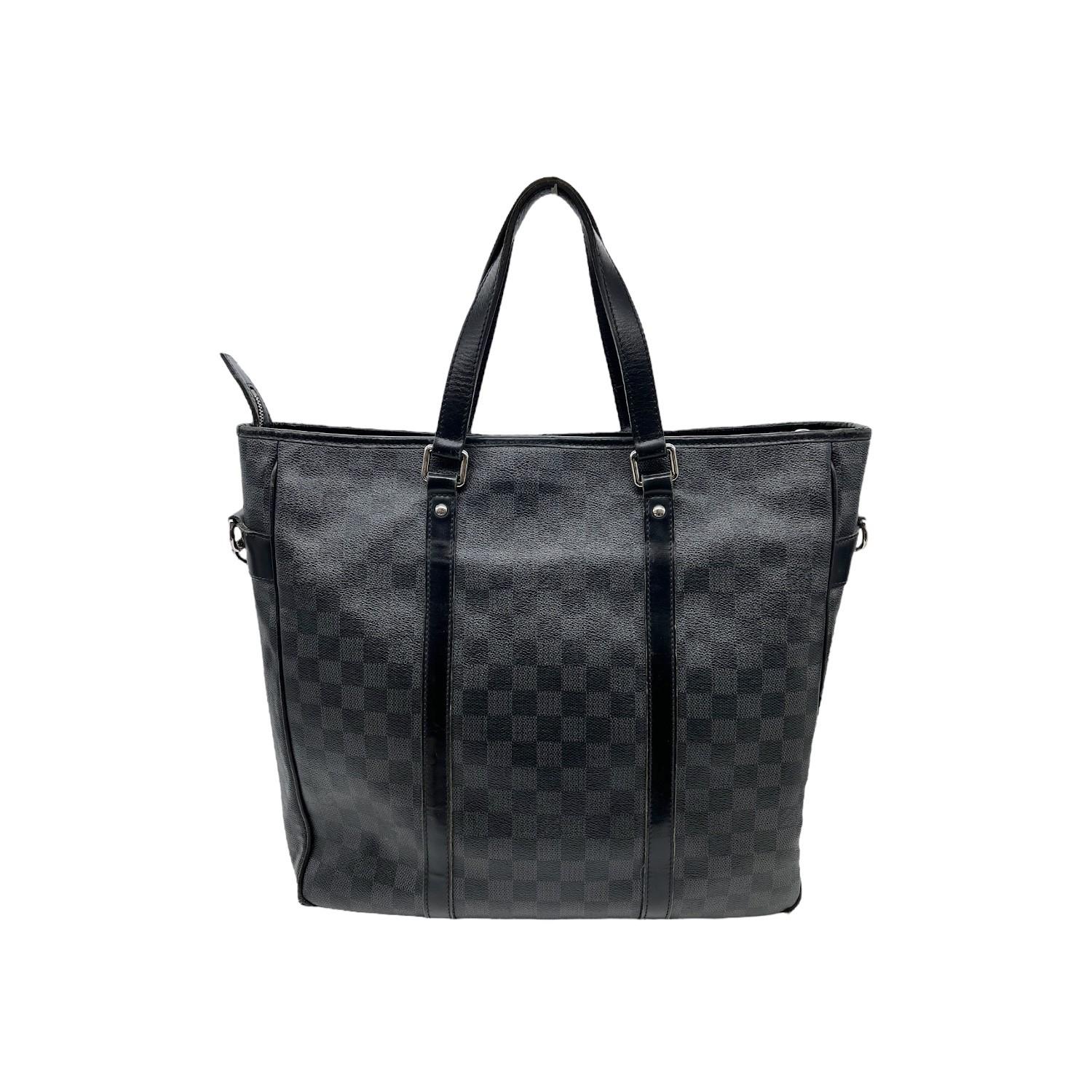 This Louis Vuitton Tadao MM was made in 2011 in France and it is finely crafted of Louis Vuitton's Damier Graphite coated canvas with black leather trimmings and silver-tone hardware features. It has flat black leather top handles and it comes with