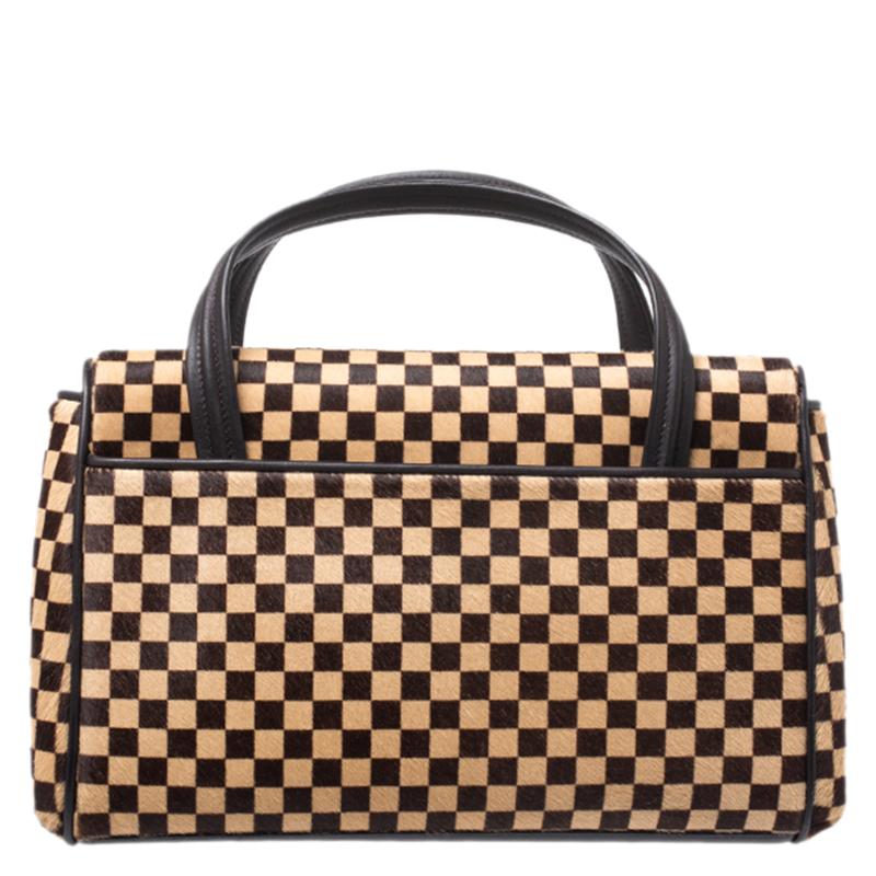 In this limited edition piece, Louis Vuitton's Damier comes alive on calf hair to win your heart and closet. The Lionne Spawn bag has a flap with a snap button securing the Alcantara interior for your essentials. Held by two top handes, you will