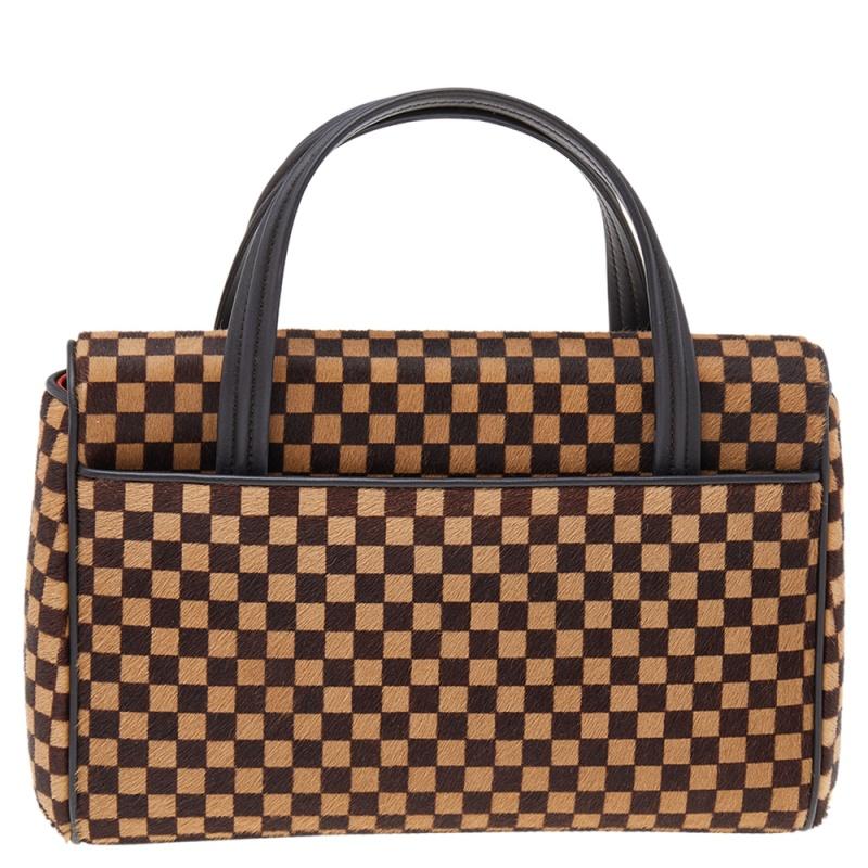 In this limited edition piece, Louis Vuitton's Damier comes alive on calf hair to win your heart and closet. The Lionne Spawn bag has a flap with a snap button securing the Alcantara interior for your essentials. Held by two top handles, you will