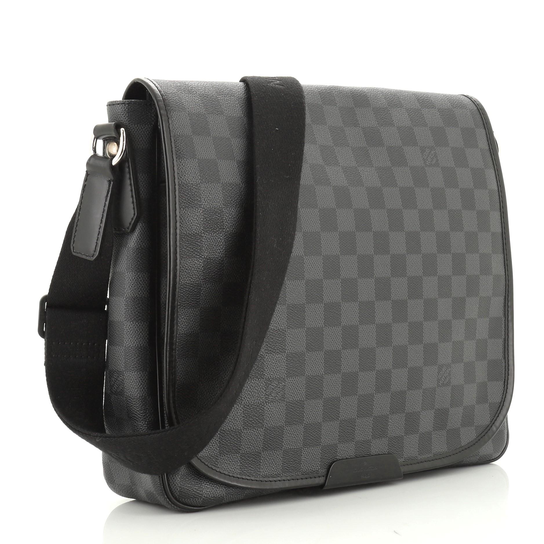 This Louis Vuitton Daniel Messenger Bag Damier Graphite MM, crafted from damier graphite coated canvas, features an adjustable canvas strap, exterior back zip pocket and silver-tone hardware. Its magnetic snap closure opens to a black fabric