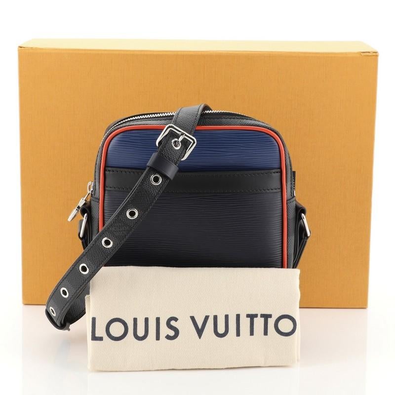 This Louis Vuitton Danube Handbag Epi Leather and Damier Graphite Slim, crafted from blue epi leather and damier graphite, features an adjustable strap, exterior front slip pocket, and silver-tone hardware. Its zip closure opens to a black fabric