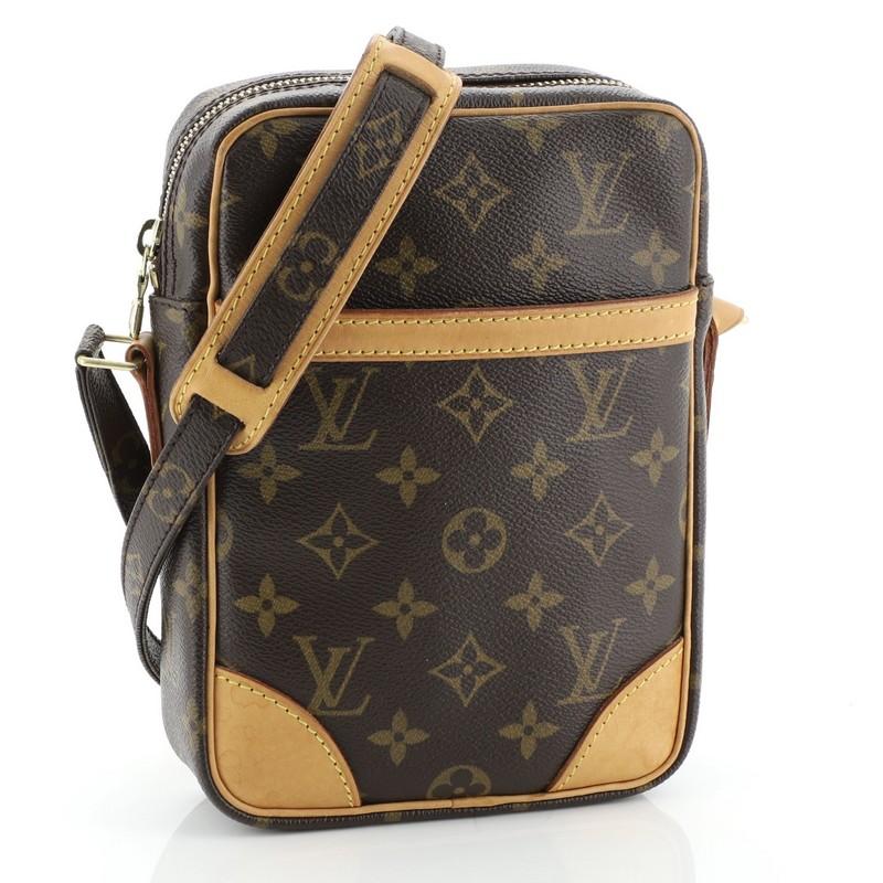 This Louis Vuitton Danube Handbag Monogram Canvas, crafted from brown monogram coated canvas, features adjustable strap with leather pad, exterior front slip pocket and gold-tone hardware. Its top zip-around closure opens to a brown leather