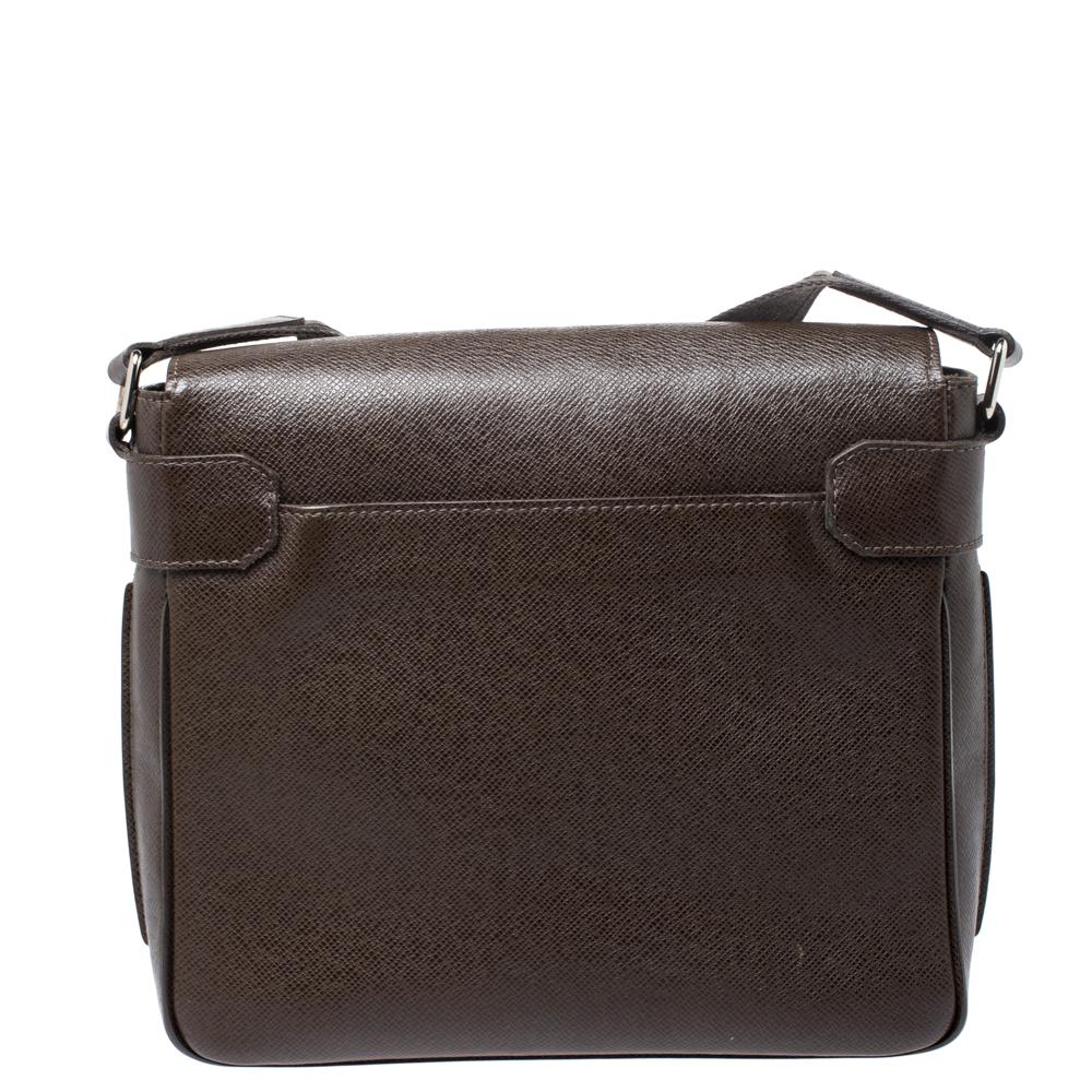 Every modern-day wardrobe needs a Louis Vuitton bag like this. Accentuate your style by carrying this bag that is stylish, subtle and functional. Crafted in France, it is created from Taiga leather and comes in a lovely shade of dark brown. It