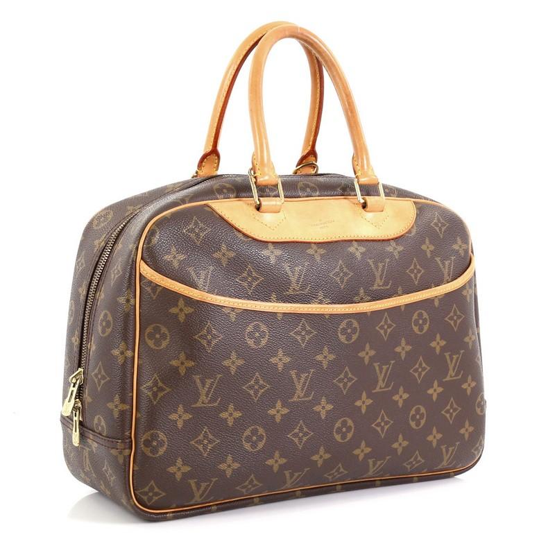 This Louis Vuitton Deauville Handbag Monogram Canvas, crafted in brown monogram coated canvas, features dual rolled vachetta leather handles and trim, exterior front slip pocket, and gold-tone hardware. Its top zip closure opens to a neutral canvas