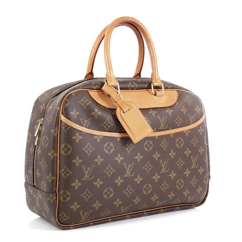 This Louis Vuitton Deauville Handbag Monogram Canvas, crafted in brown monogram coated canvas, features dual rolled vachetta leather handles and trim, exterior front slip pocket, and gold-tone hardware. Its top zip closure opens to a neutral canvas