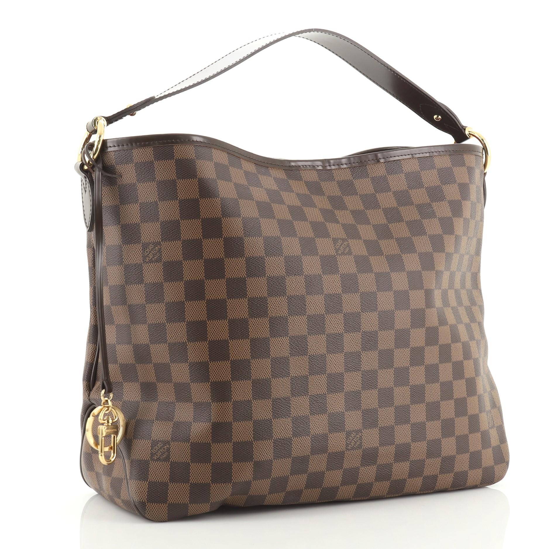 This Louis Vuitton Delightful NM Handbag Damier MM is a versatile hobo that can be used every day. Crafted in Damier ebene coated canvas, this bag features a flat leather handle and gold-tone hardware. Its hook closure opens to a red fabric interior