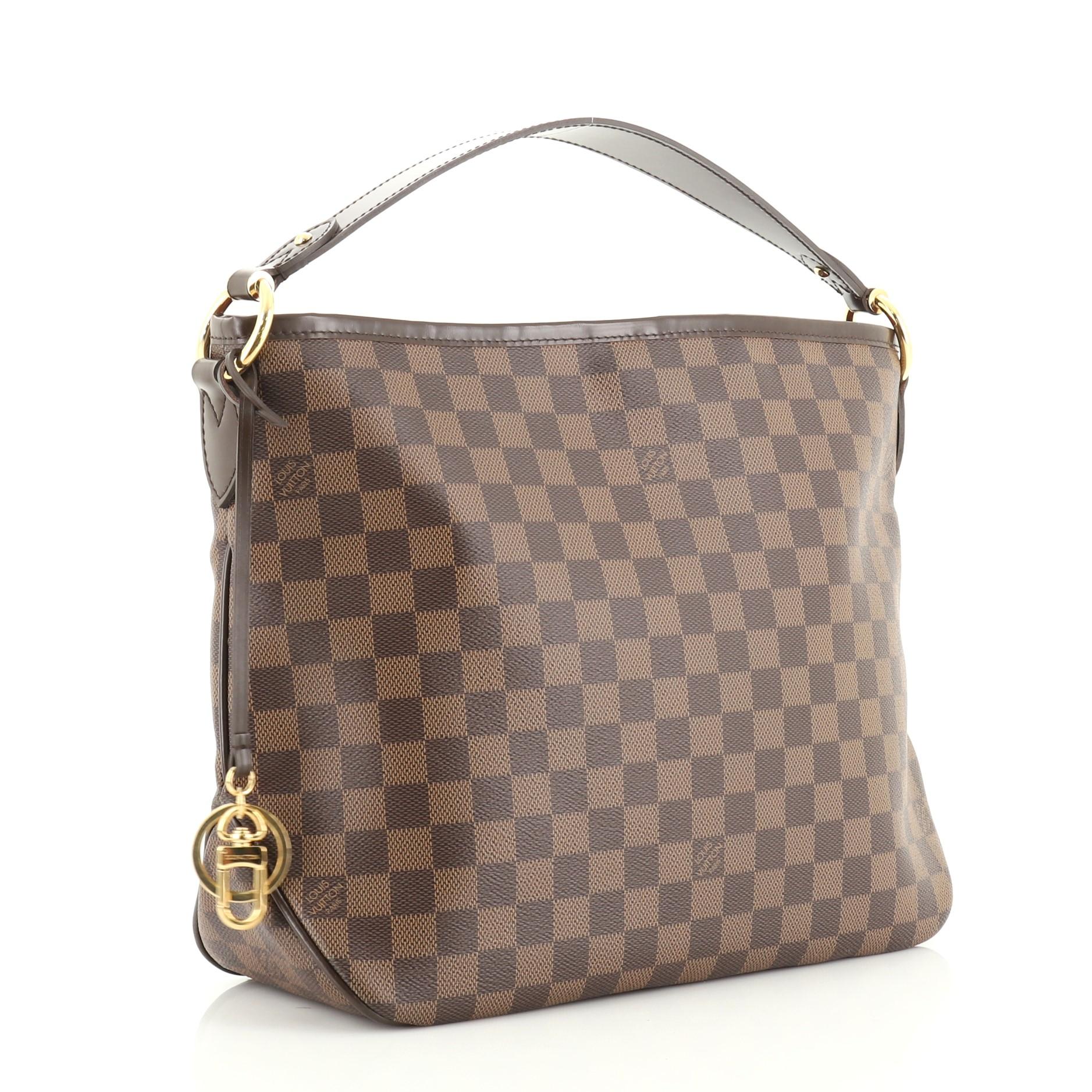 This Louis Vuitton Delightful NM Handbag Damier MM is an everyday bag with the brand's traditional design with modern flair. Crafted in damier ebene coated canvas, it features a flat leather handle and gold-tone hardware. Its hook closure opens to a