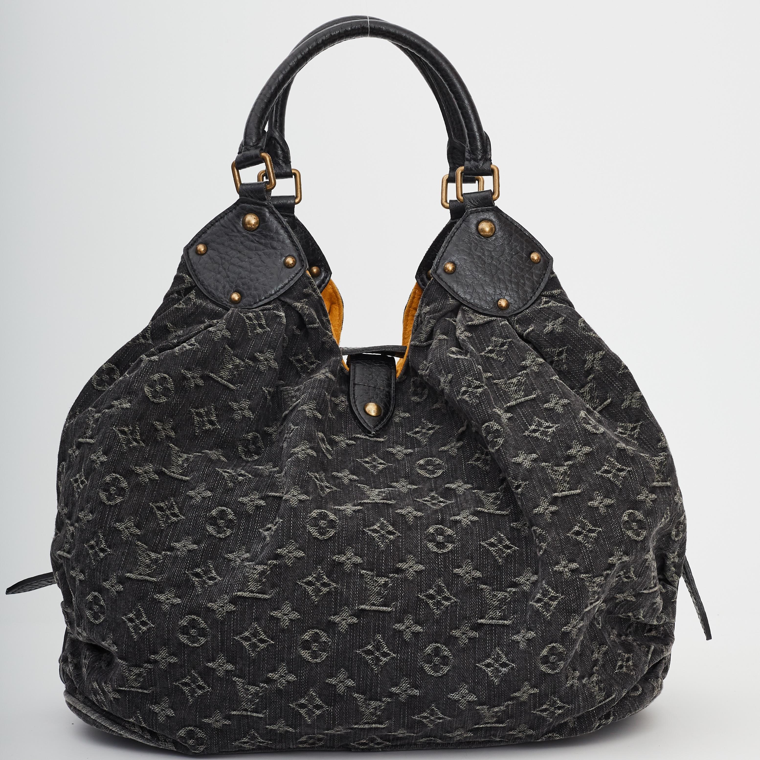 This Mahina bag is made of black supple denim with the classic Louis Vuitton monogram. It is gathered at both sides with a draped effect supported with black leather trim and rolled leather handles. The brass hardware is bold and features a
