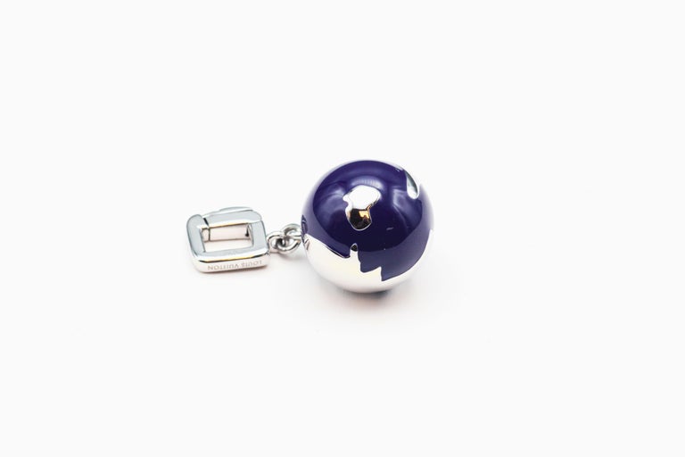 Fine diamond on enamel and 18K white gold pendant/charm in the likeness of a globe,  by Louis Vuitton. It features a blue enamel body representing the oceans, with white gold representing the bodies of land, and a small diamond set in what appears