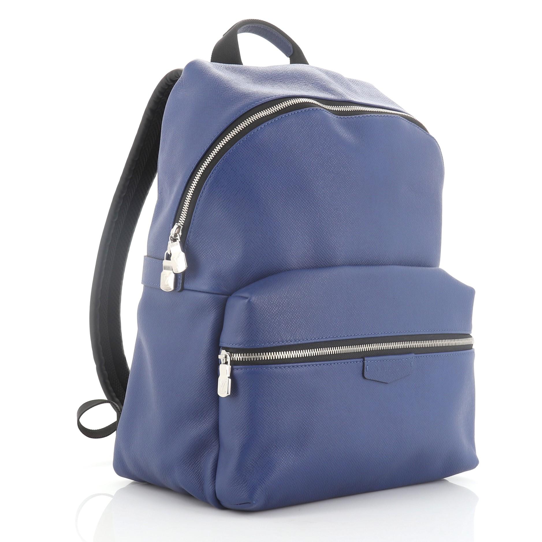 This Louis Vuitton Discovery Backpack Taiga Leather PM, crafted in blue Taiga leather, features adjustable shoulder straps, exterior front zip pocket and silver-tone hardware. Its zip closure opens to a black fabric interior with slip pockets.