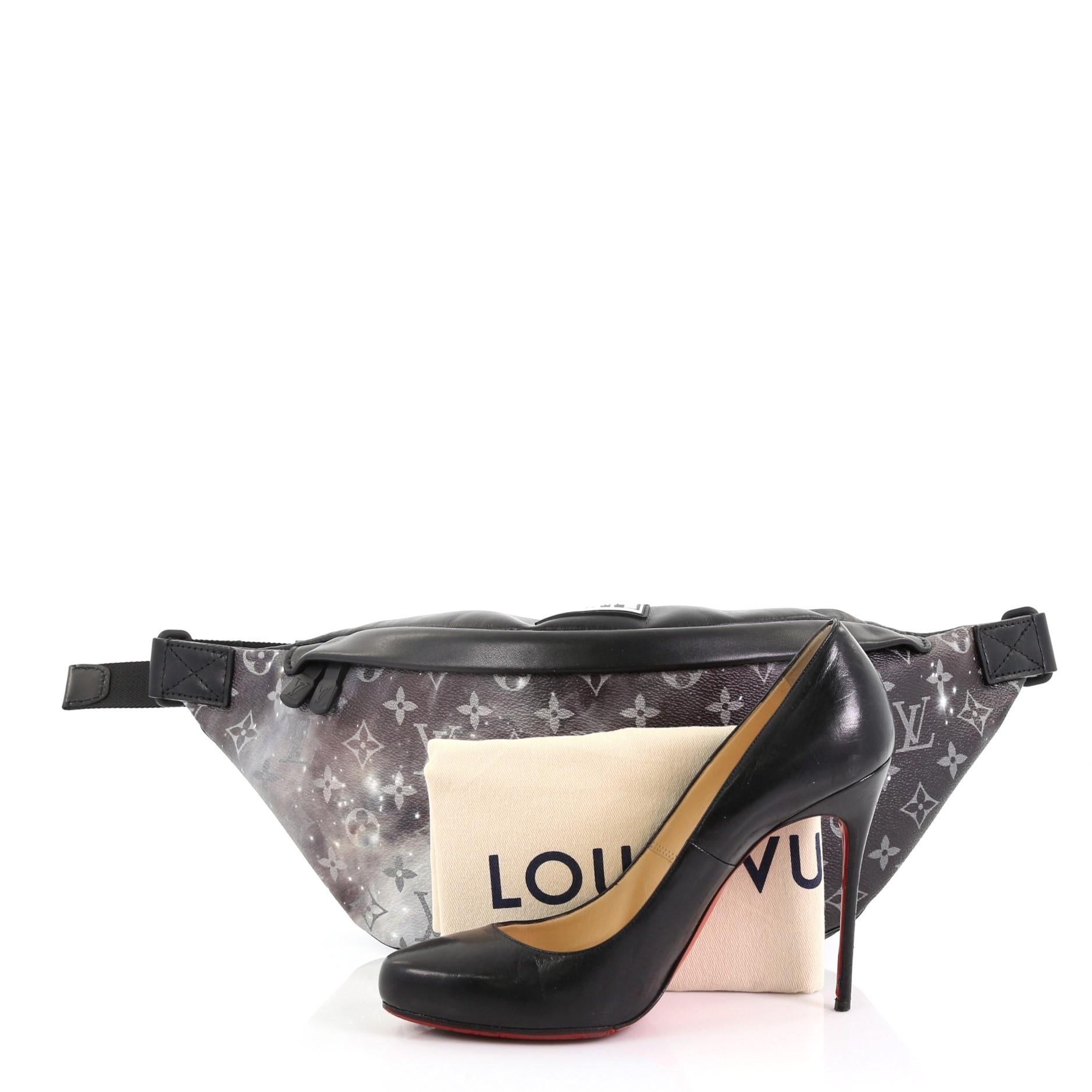 This Louis Vuitton Discovery Bumbag Limited Edition Monogram Galaxy Canvas, crafted in monogram Galaxy coated canvas, features an adjustable belt strap, exterior zipped pockets, and black gunmetal-tone hardware. Its zip closure opens to a black