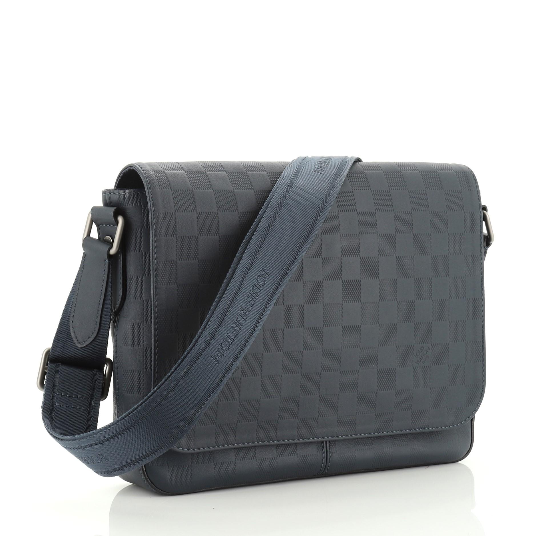 This Louis Vuitton District Messenger Bag Damier Infini Leather PM, crafted from damier infini leather, features an adjustable textile shoulder strap, exterior back zip pocket and matte gunmetal-tone hardware. Its flap opens to a blue fabric
