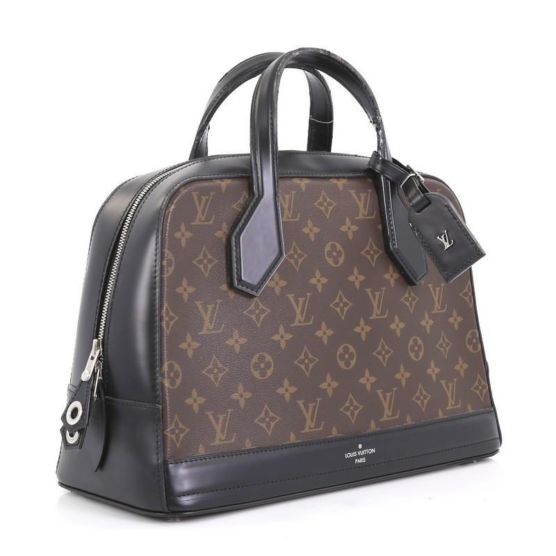 This Louis Vuitton Dora Handbag Monogram Canvas and Calf Leather MM, crafted from brown monogram coated canvas and black calf leather, features dual flat leather top handles, leather trim, and silver-tone hardware. Its two-way zip closure opens to a